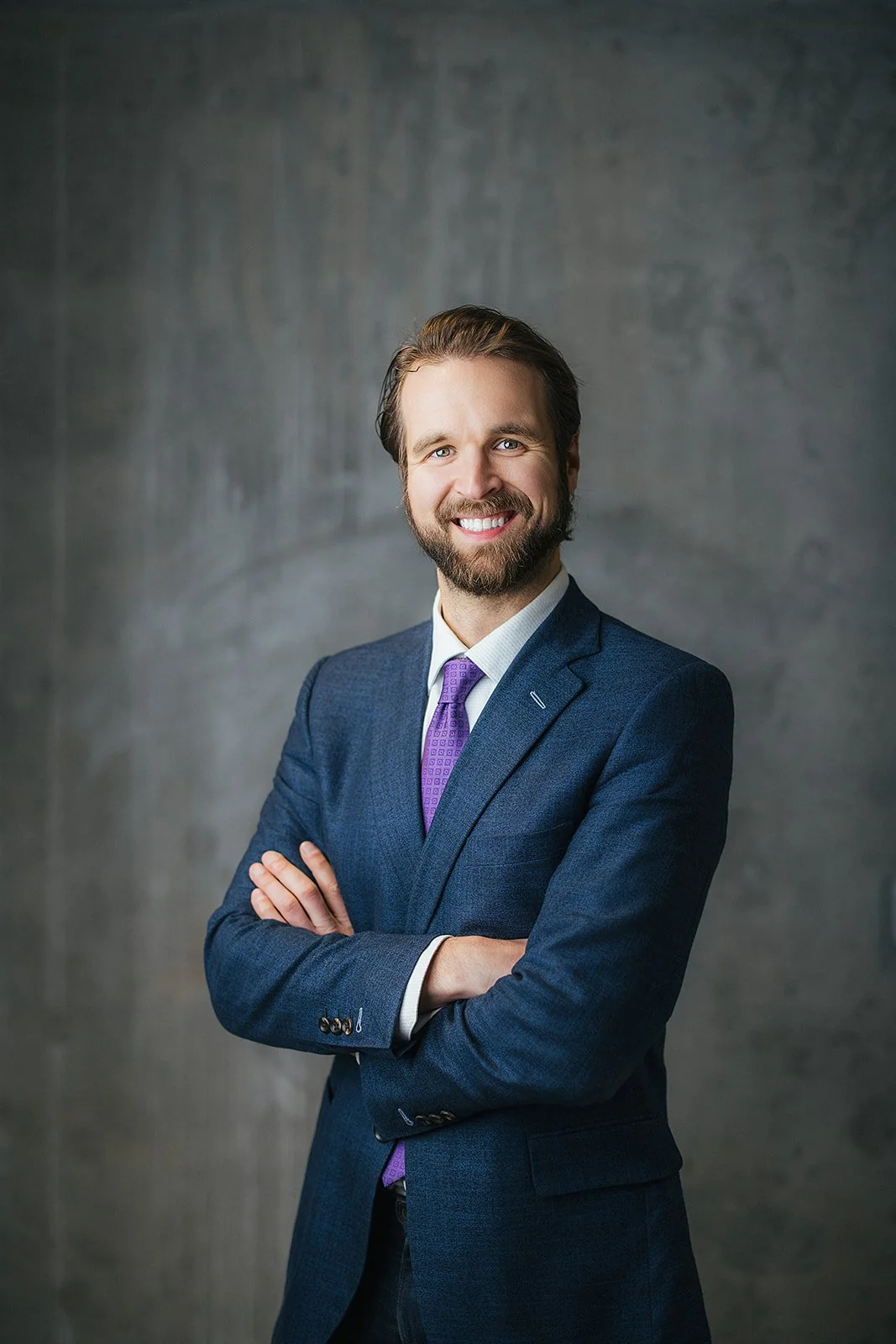 Man in Blue Blazer and Purple Tie Smiling During Professional Headshot Session