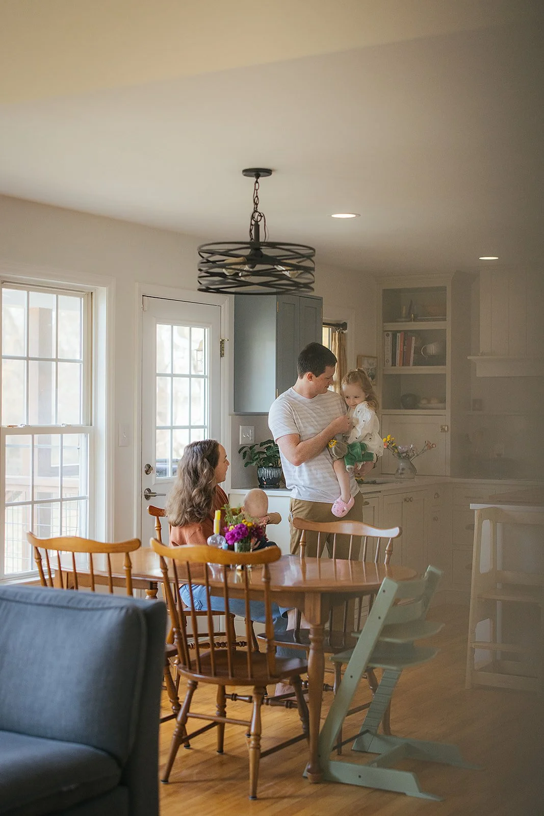 Family of four together in bright dining room during Durham in-home lifestyle family photography session