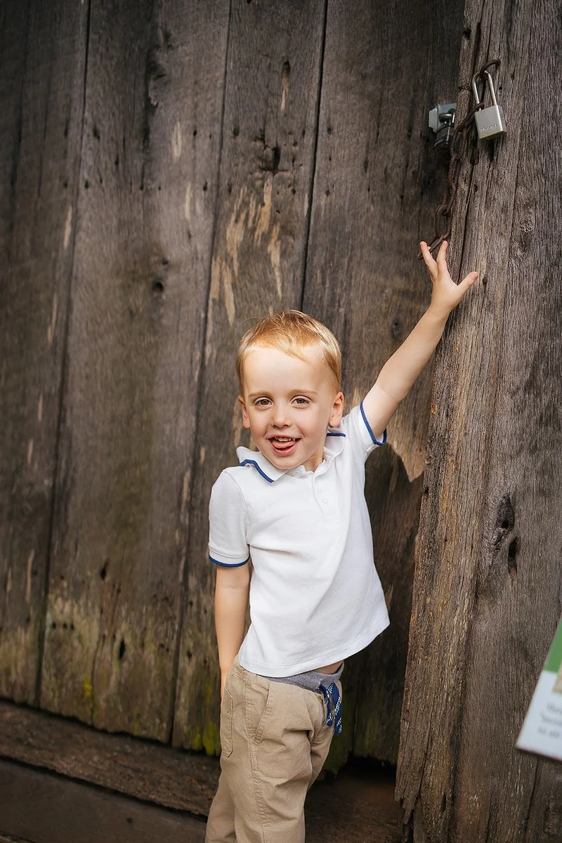 Young boy standing in front of old wooden wall