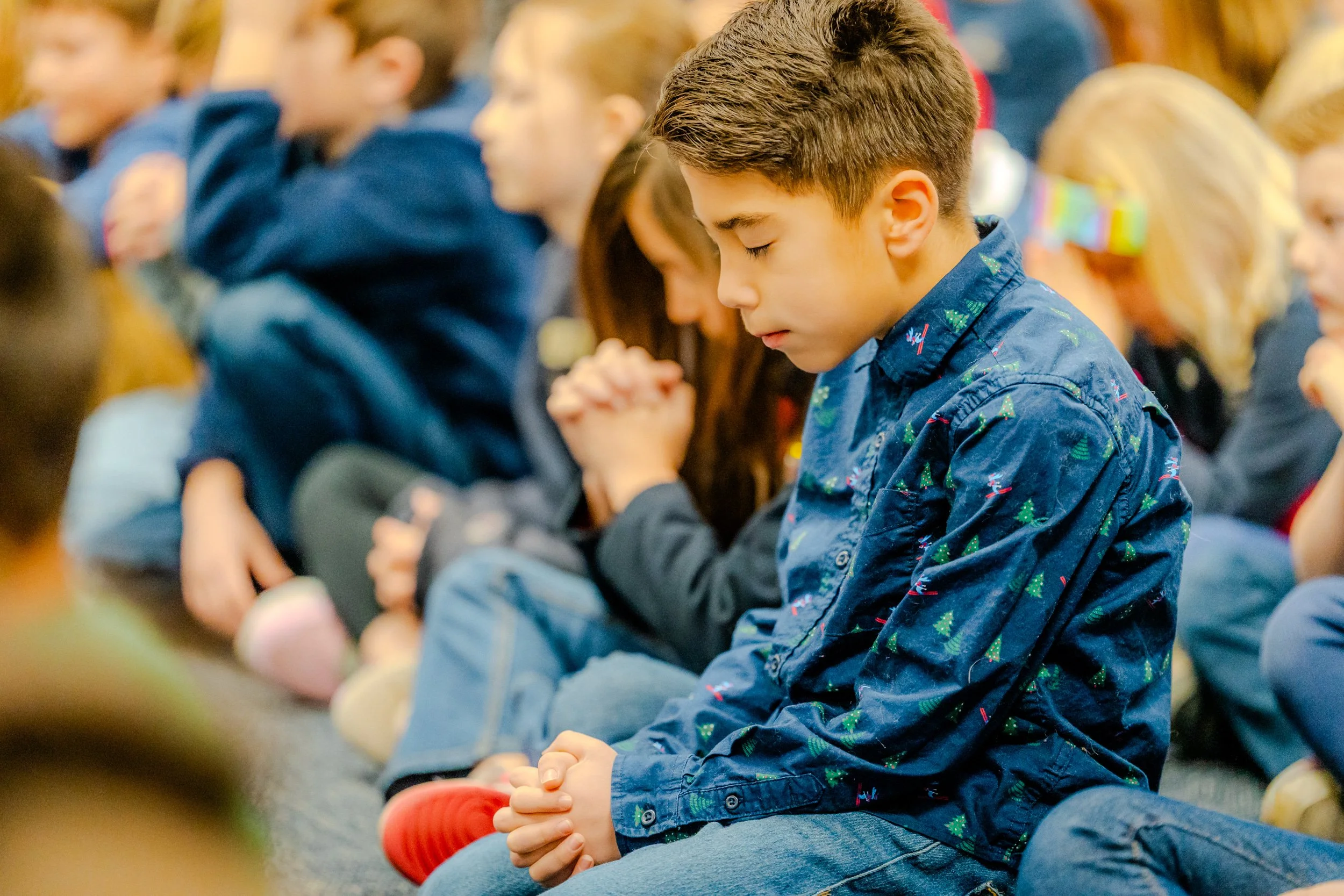 Student praying with folded hands among classmates