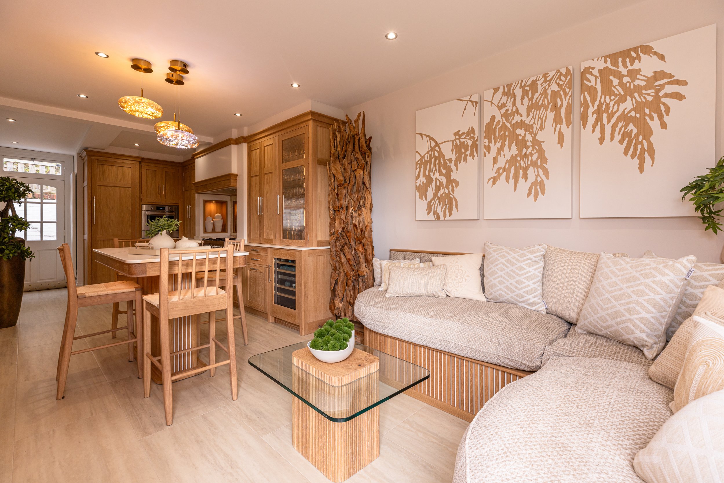 Modern living room and kitchen area with beige sofa, wooden furniture, wall art, and decorative elements. Interiors by Lucy Rebecca Photography.
