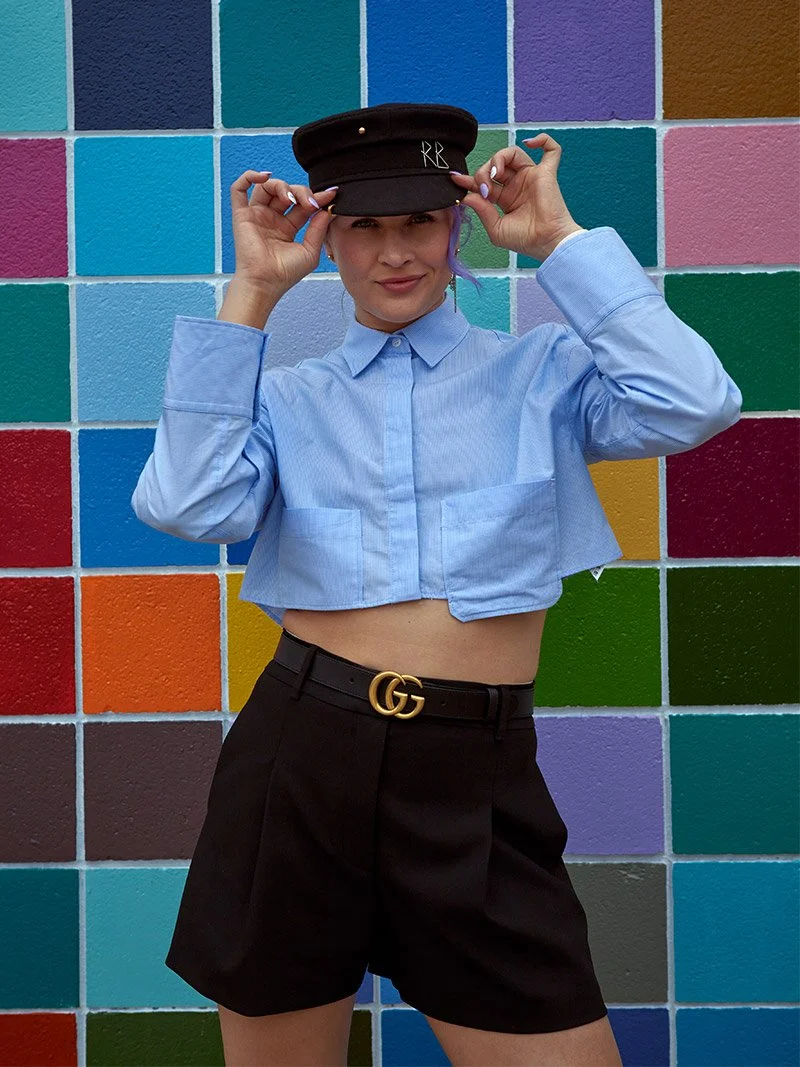 Brand photographer captures a portrait of a woman in a constructivist-inspired blue shirt and shorts, showcasing authentic details and vibrant colors.