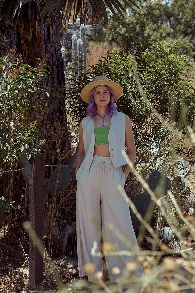Playful and youthful branding photography of a woman in wide leg pants and a safari-style vest. Studio portrait with a neo-renaissance touch, perfect for personal branding