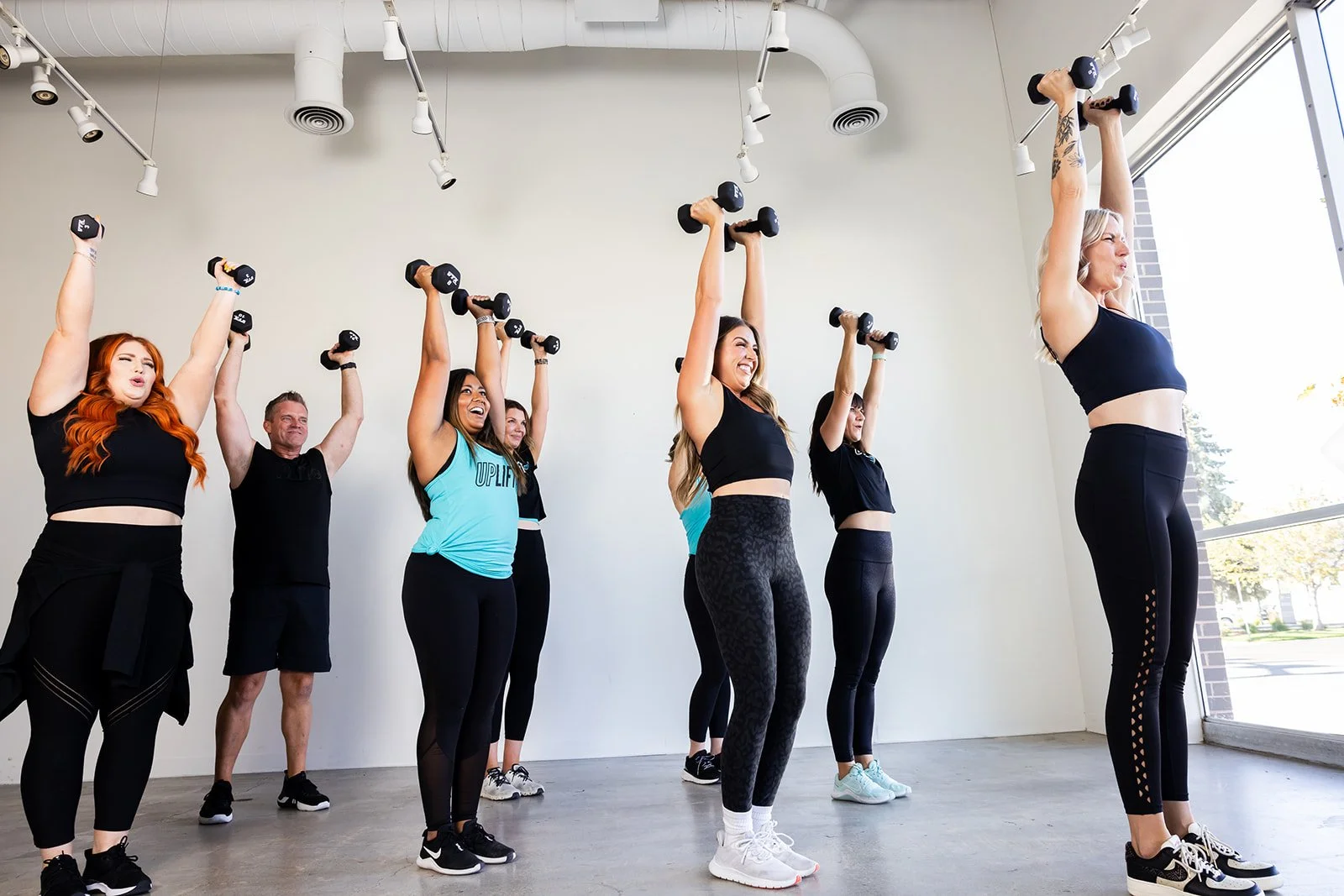 group fitness class with participants raising weights over their heads