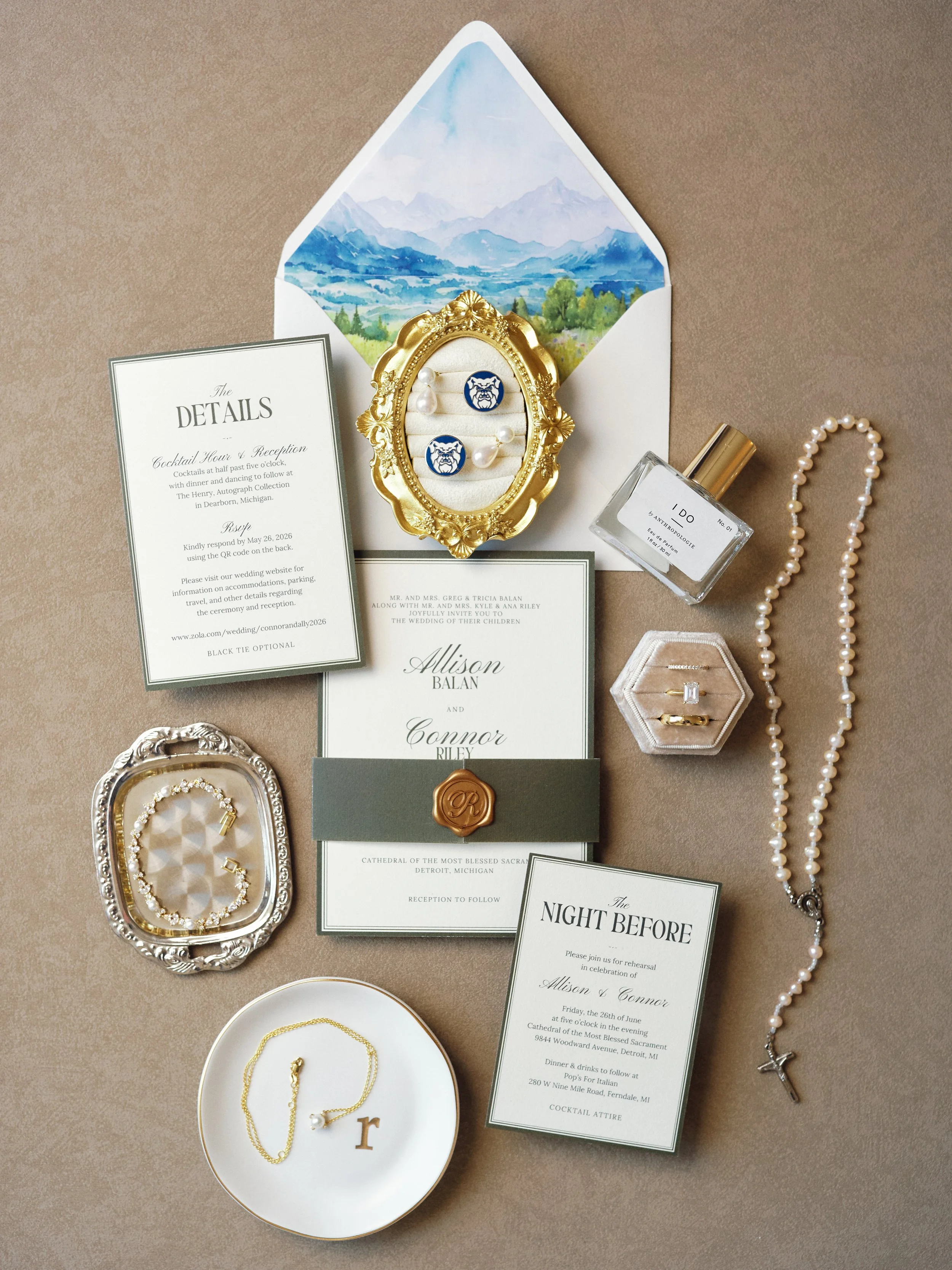 Wedding flat lay image including wedding rings, invitations, a rosary, a necklace, and accessories. Photographed at The Henry Hotel in Dearborn, Michigan.