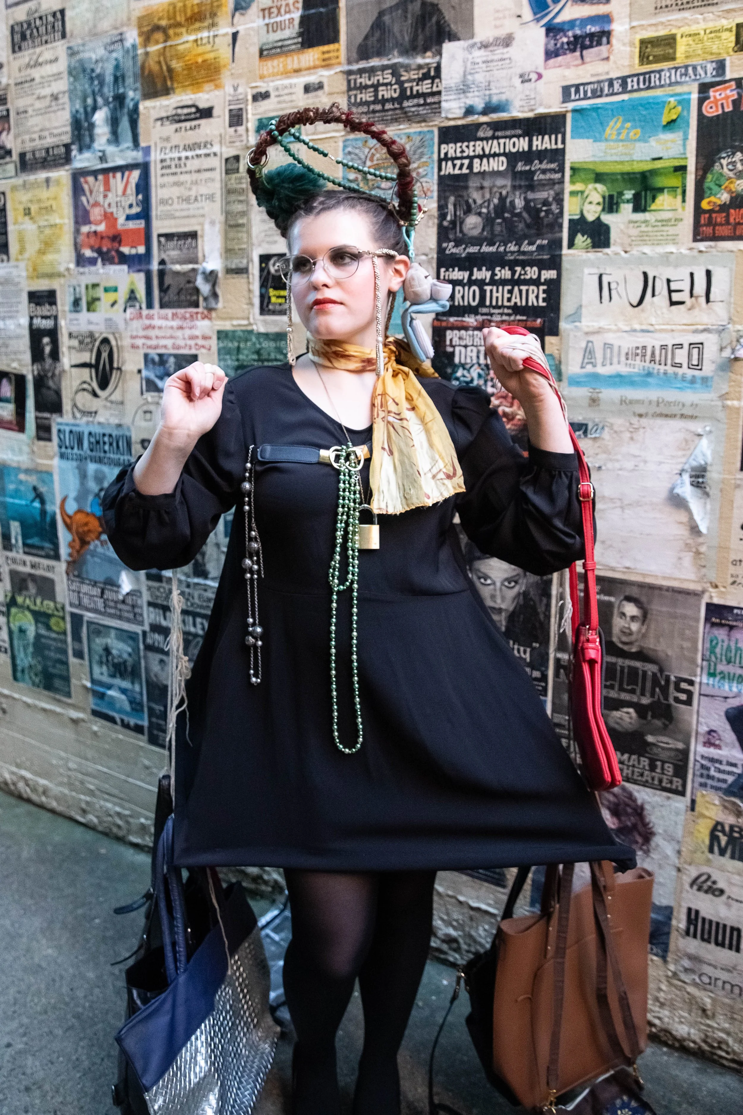 FashionTeens Santa Cruz student model wearing a black dress with multiple purses and bags attached, representing the unseen emotional baggage people carry, displayed as part of a wearable art design.