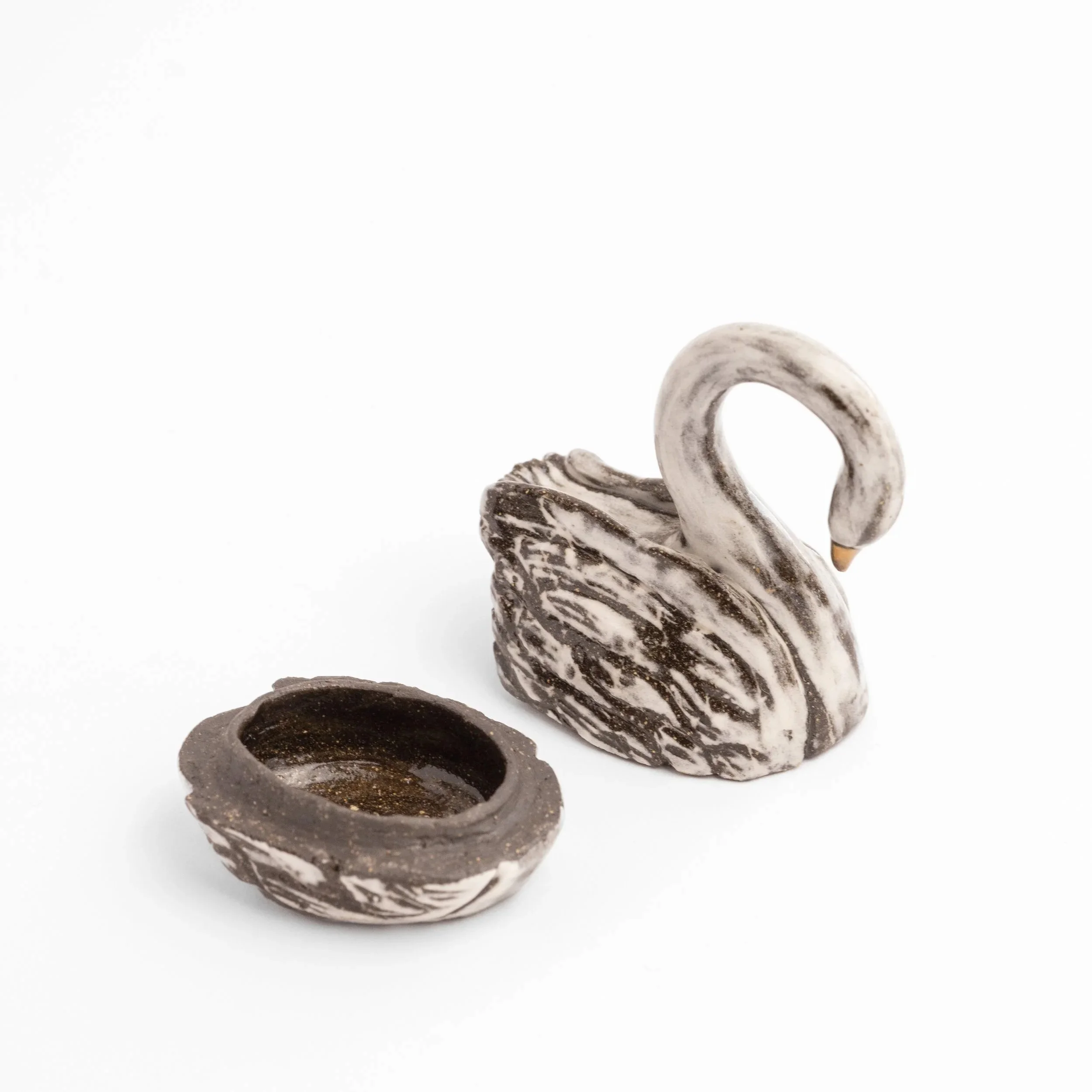 A handmade swan ceramic trinket box in two pieces. The base to the left and the top to the right against a white background