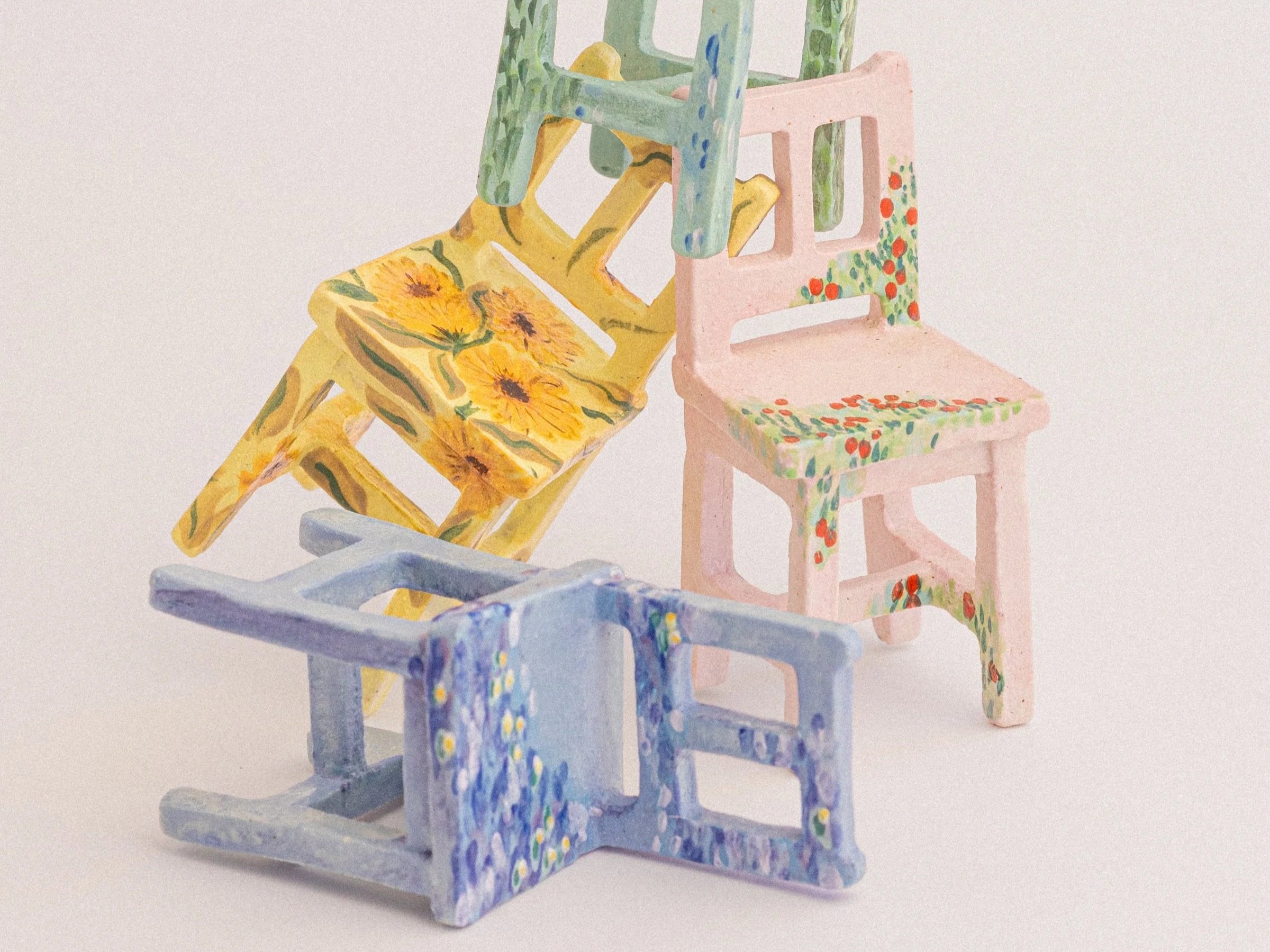 Colourful miniature ceramic chair sculptures painted with floral and abstract patterns.