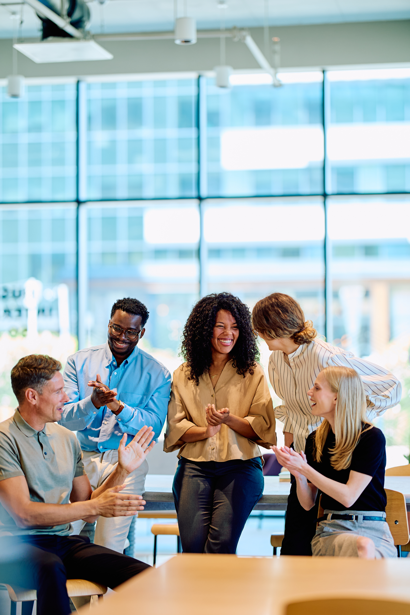 diverse group of co-workers smiling at each other in a lit office