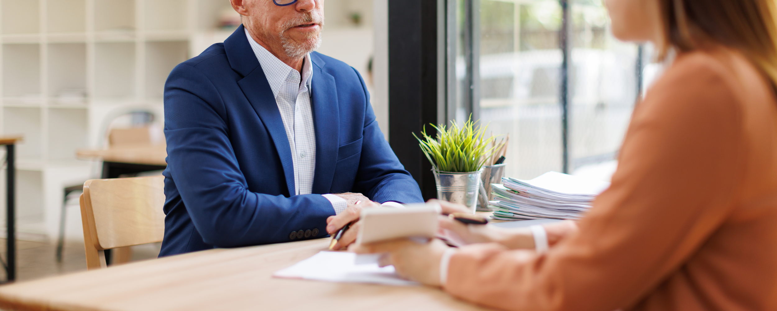 older male broker speaking with a client in their office