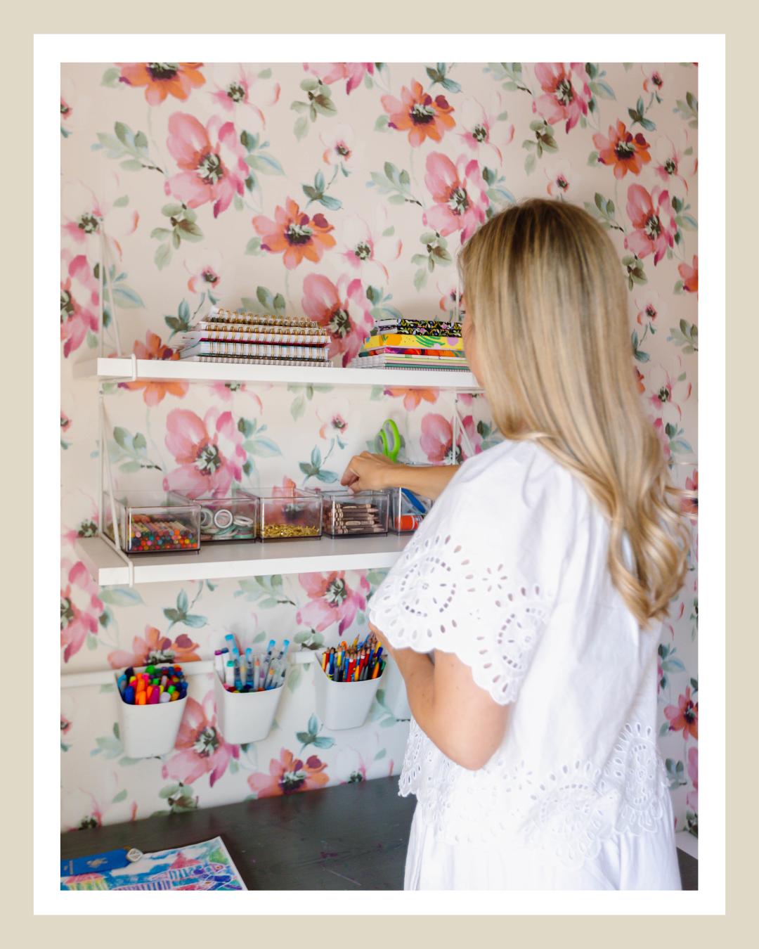 Organized kids craft station with colorful school supplies and storage in a floral playroom
