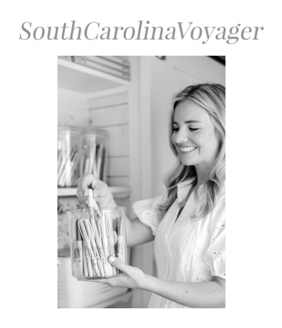 A woman smiling and holding a glass jar filled with markers in a room with shelves and jars in the background.
