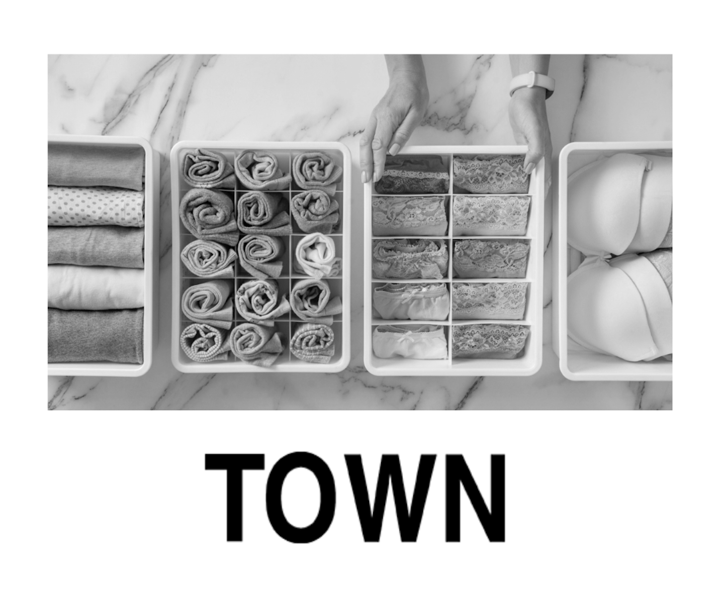 Top-down view of three organized boxes of folded laundry, including towels, bras, and underwear, on a marble surface, with the word 'TOWN' below.