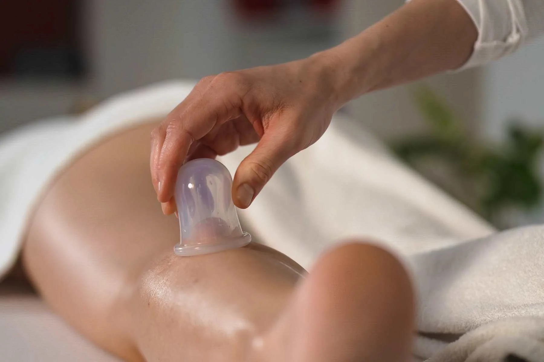 A person using a silicone cup for a  cupping massage therapy treatment on a person's leg