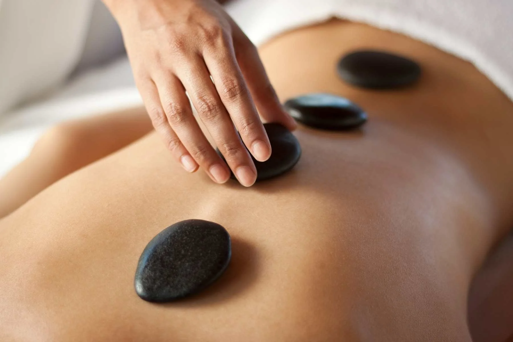Polished hot stones being used for a massage on a clients back