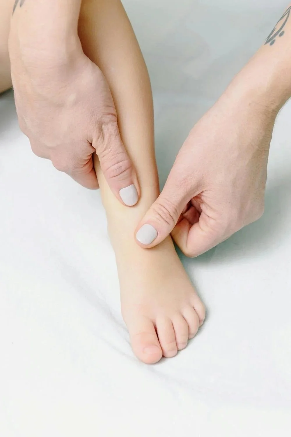 Close-up of hands massaging a baby's foot.
