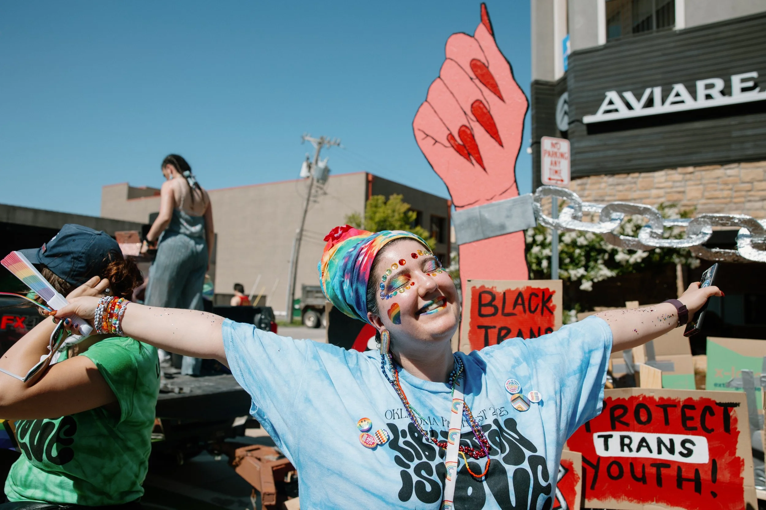 A PrideFest volunteer spreading their arms and smiling.