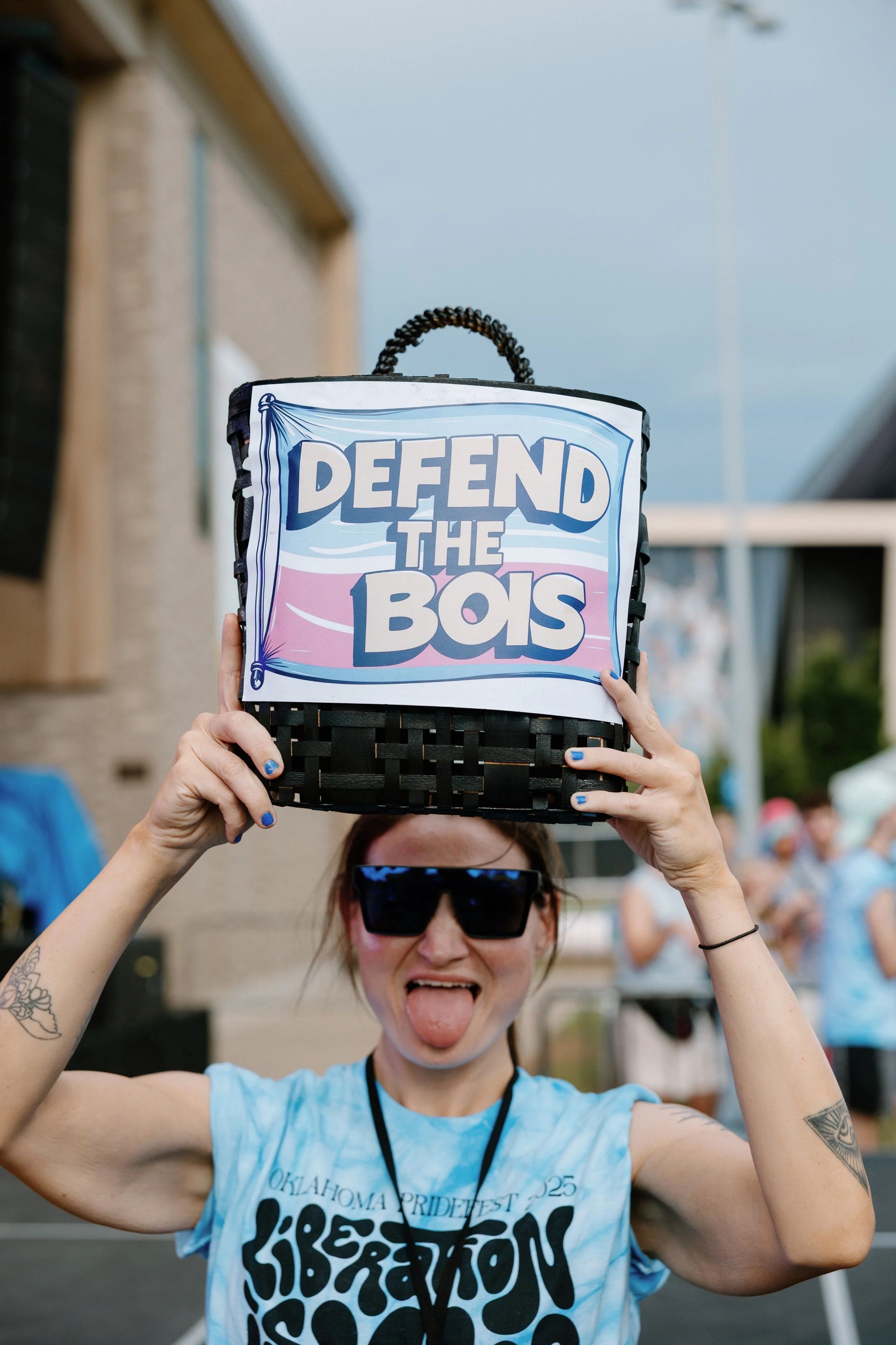 A PrideFest volunteer holding up a "Defend the Bois" sign.