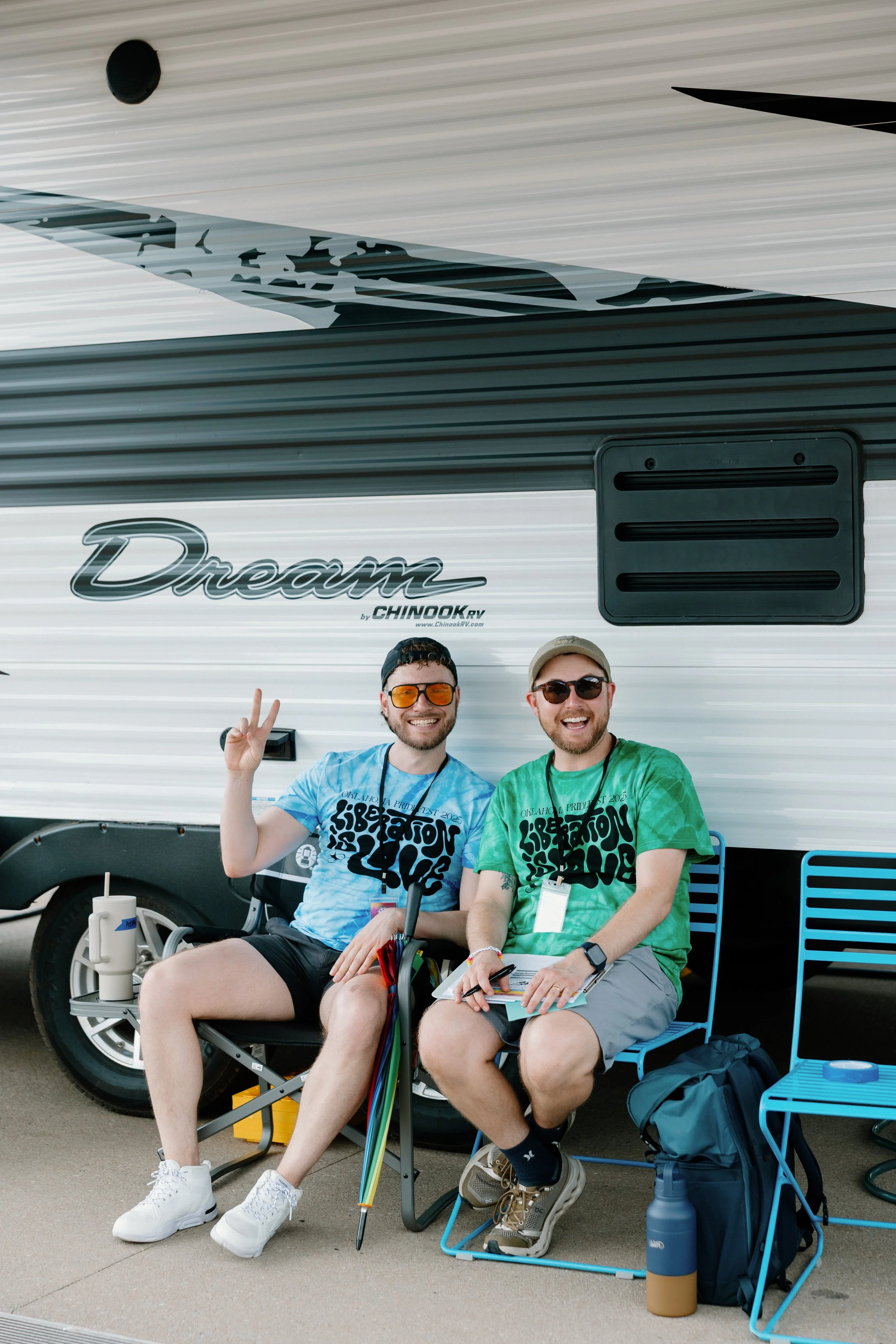 Two PrideFest volunteers sitting in front of a camper.