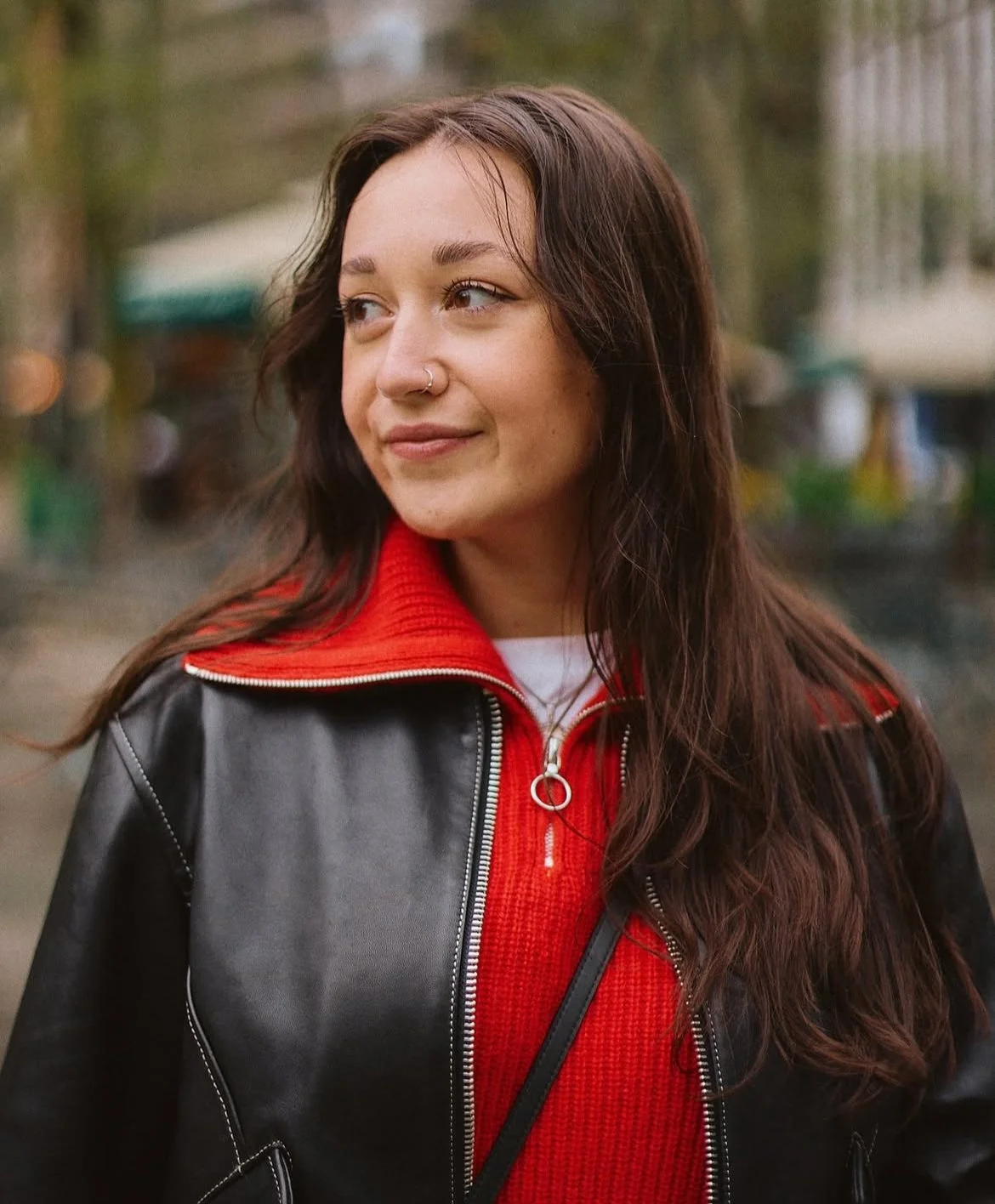 A portrait of Emma Childs in a red sweater and black leather jacket.