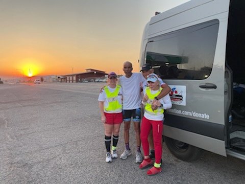 Group of runners standing next to a van at sunrise.
