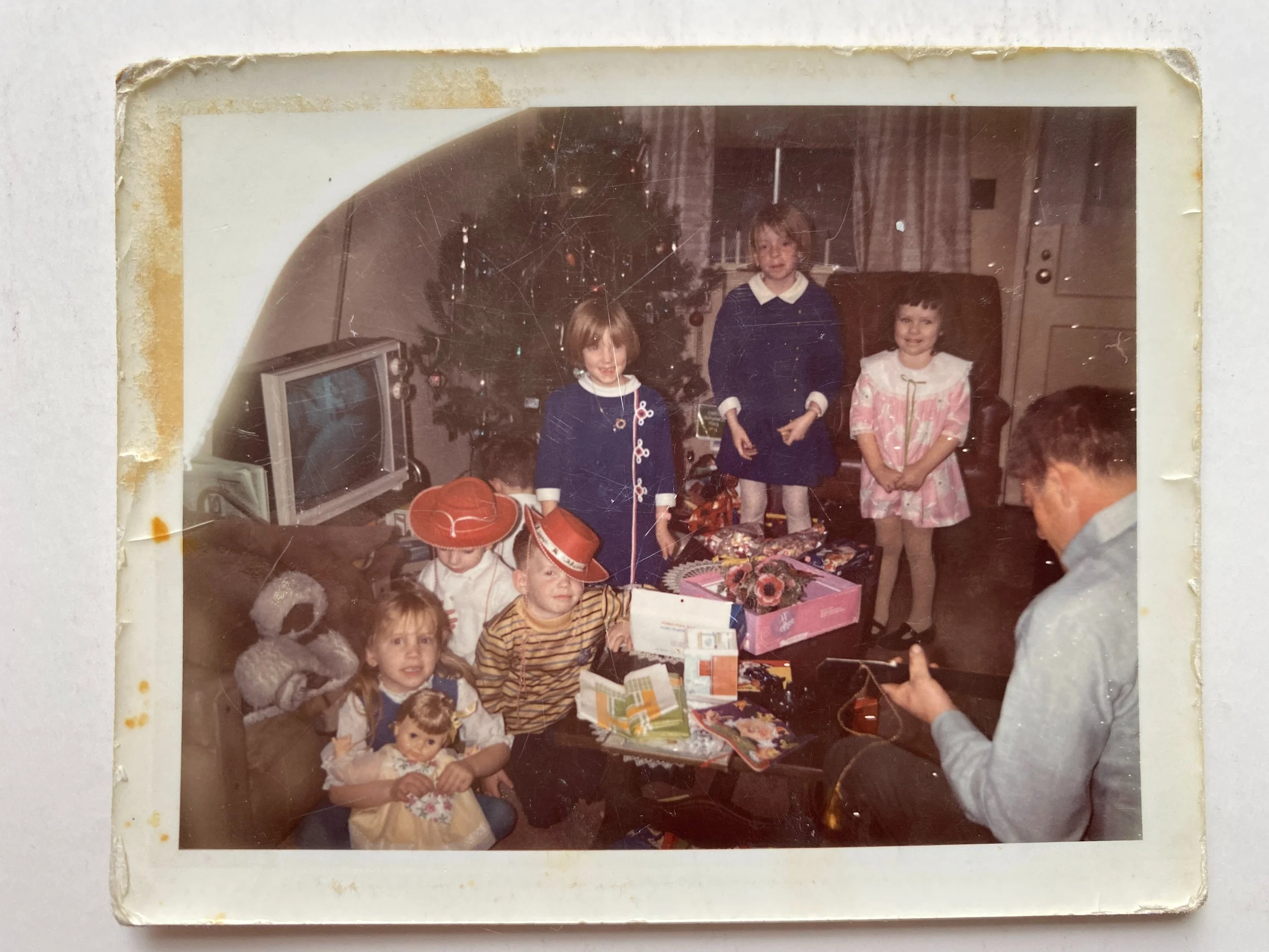 Family Christmas photo with parent playing guitar and the kids gathered by the tree.