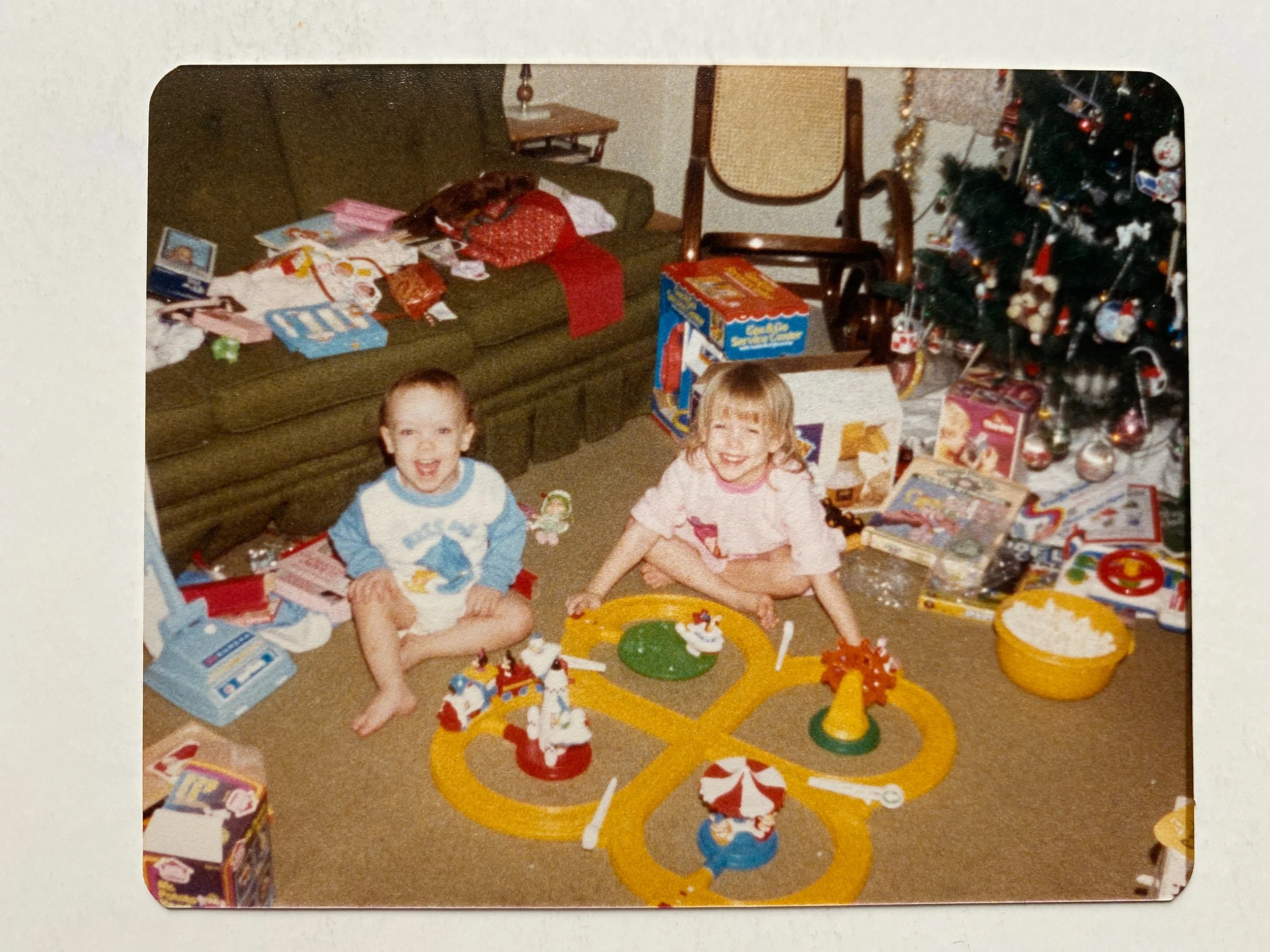 Sibling Christmas photo by the tree