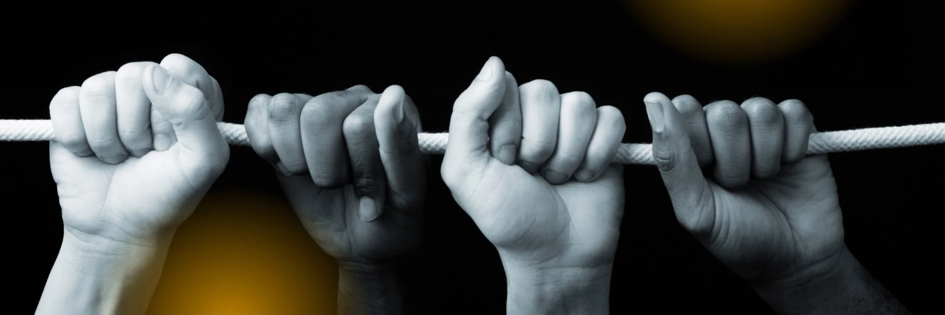 hands of different colors holding a rope together