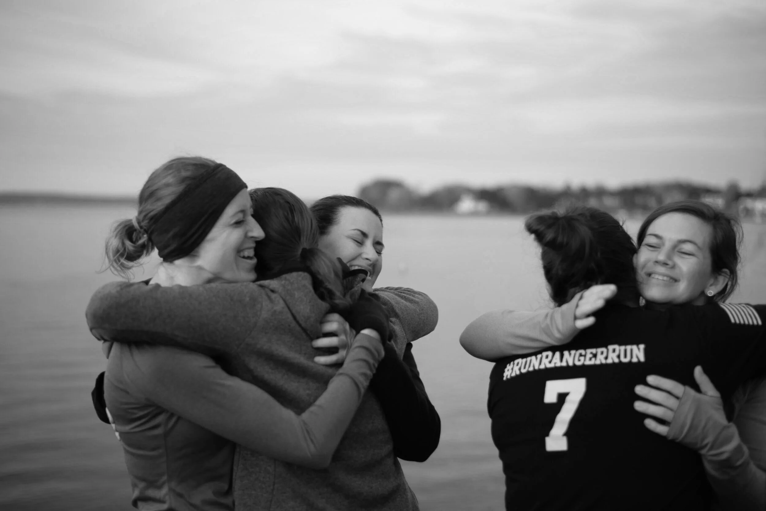 Friends laughing and embracing beside a lake