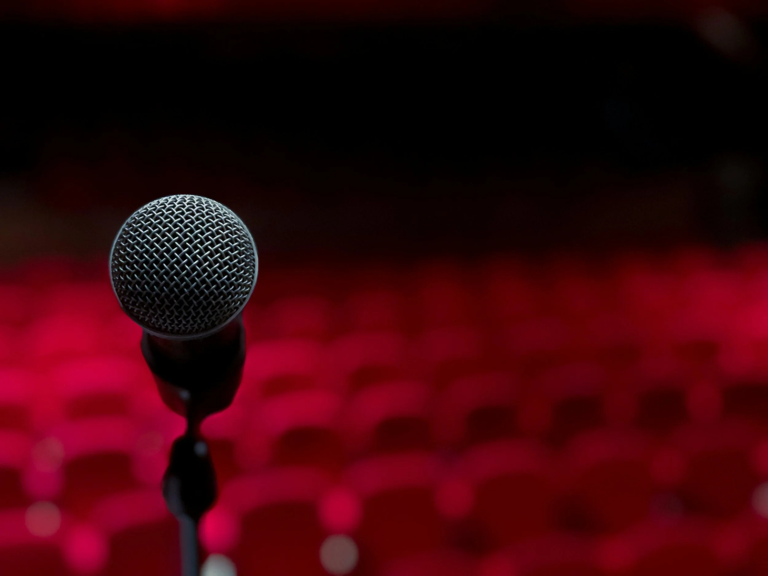 A microphone centered in front of a red and black bokeh background.
