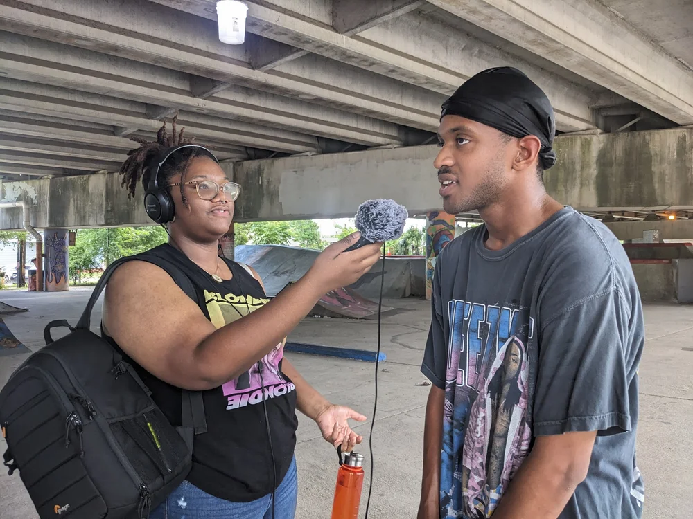 A Lede fellow interviews a young man at a skate park