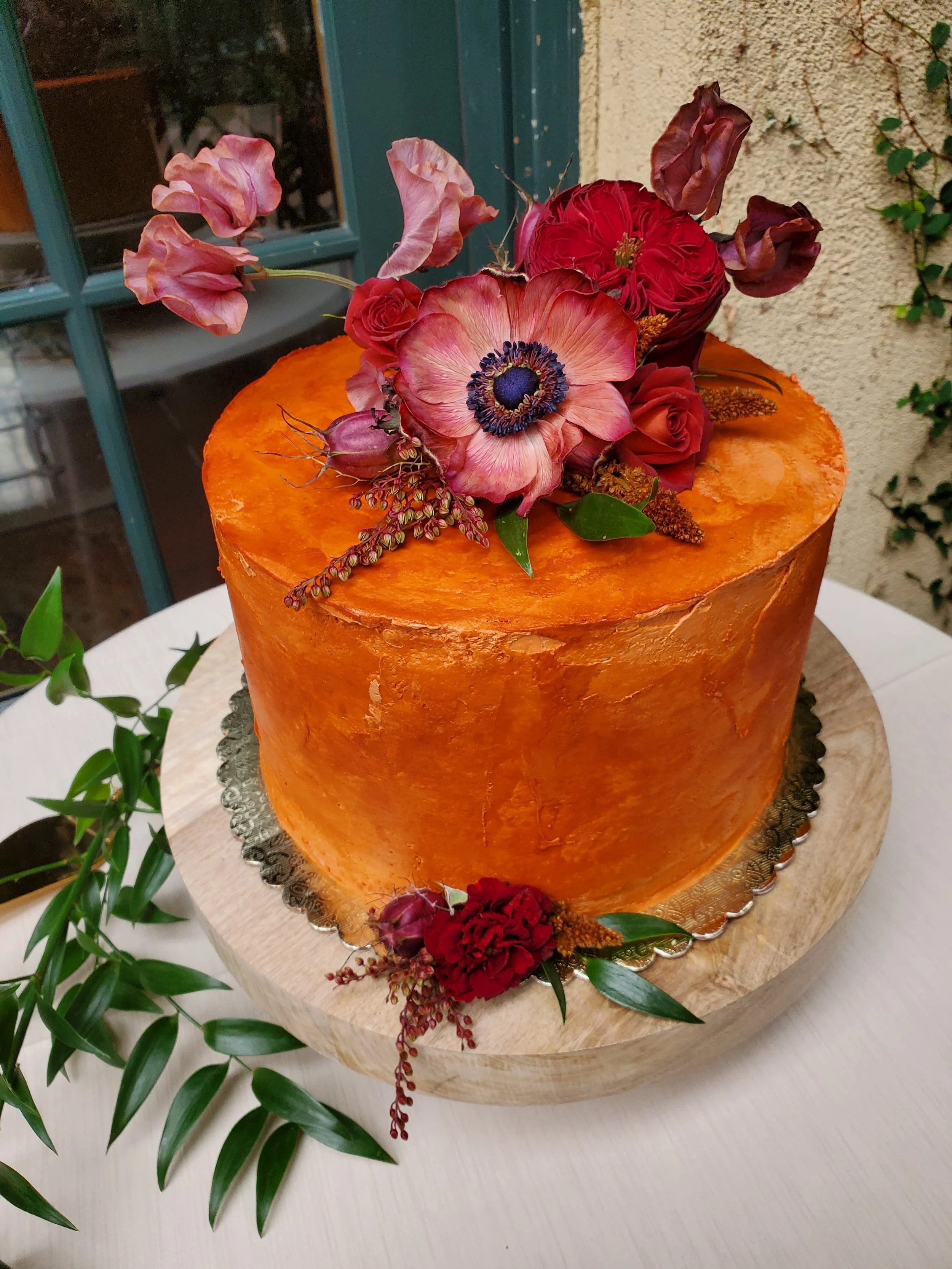   Oregon wedding cake with rich orange buttercream and floral design, styled for a Portland wedding dessert table or reception.  