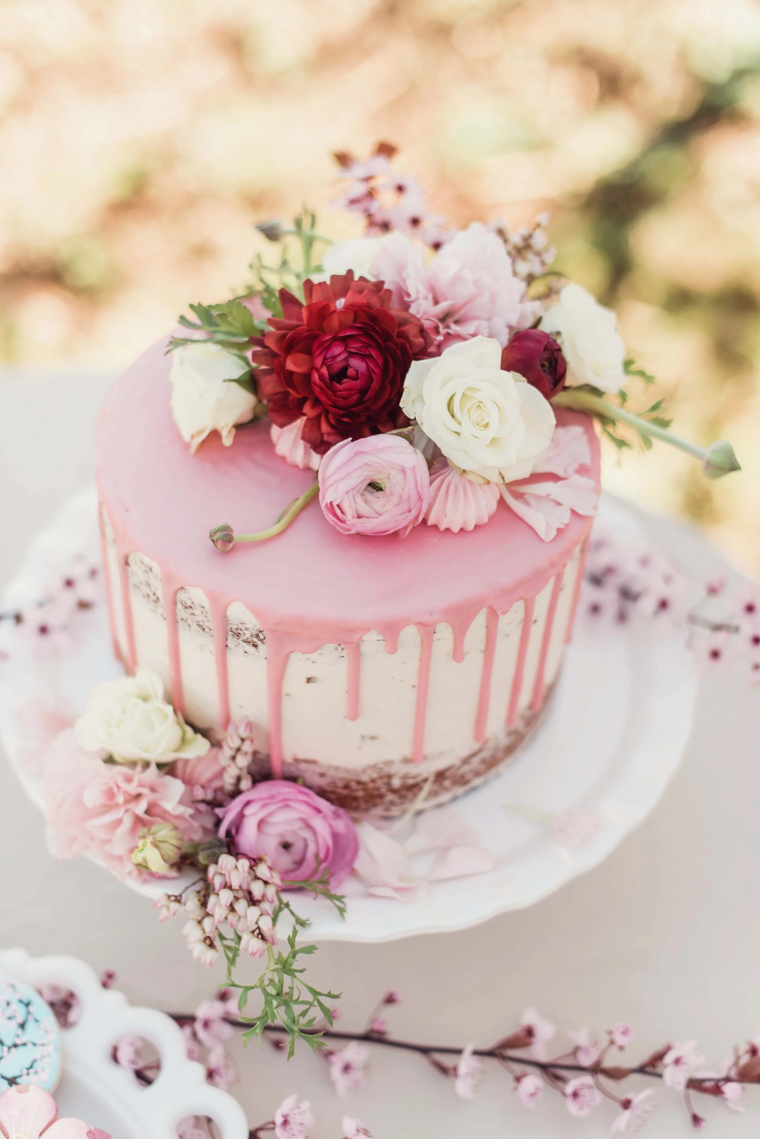   Portland Oregon wedding cake with pink drip icing and fresh floral accents, styled as a custom dessert centerpiece for a wedding reception.  
