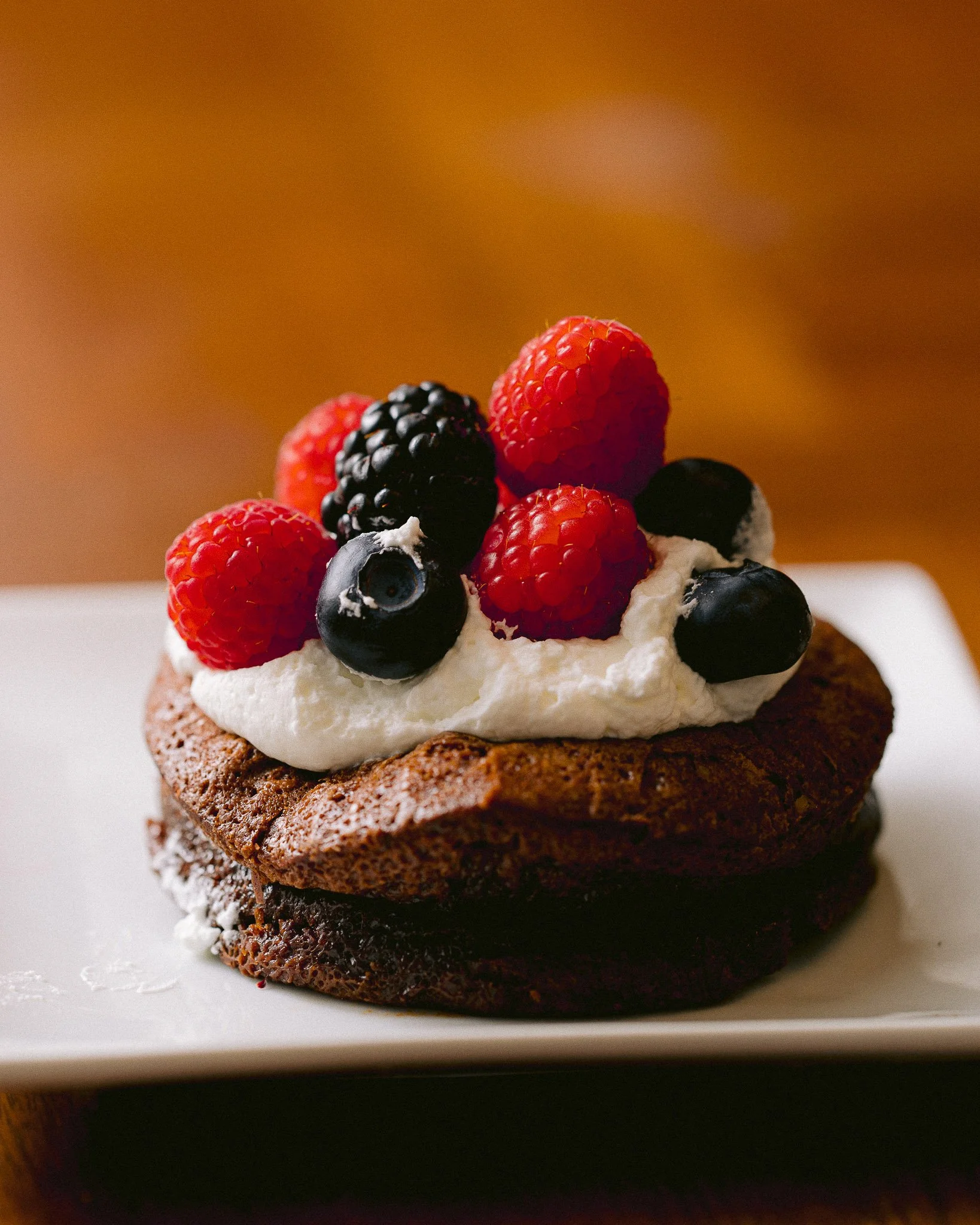   Portland Oregon wedding dessert featuring a chocolate cake topped with fresh berries and cream, styled for an elegant event table.  
