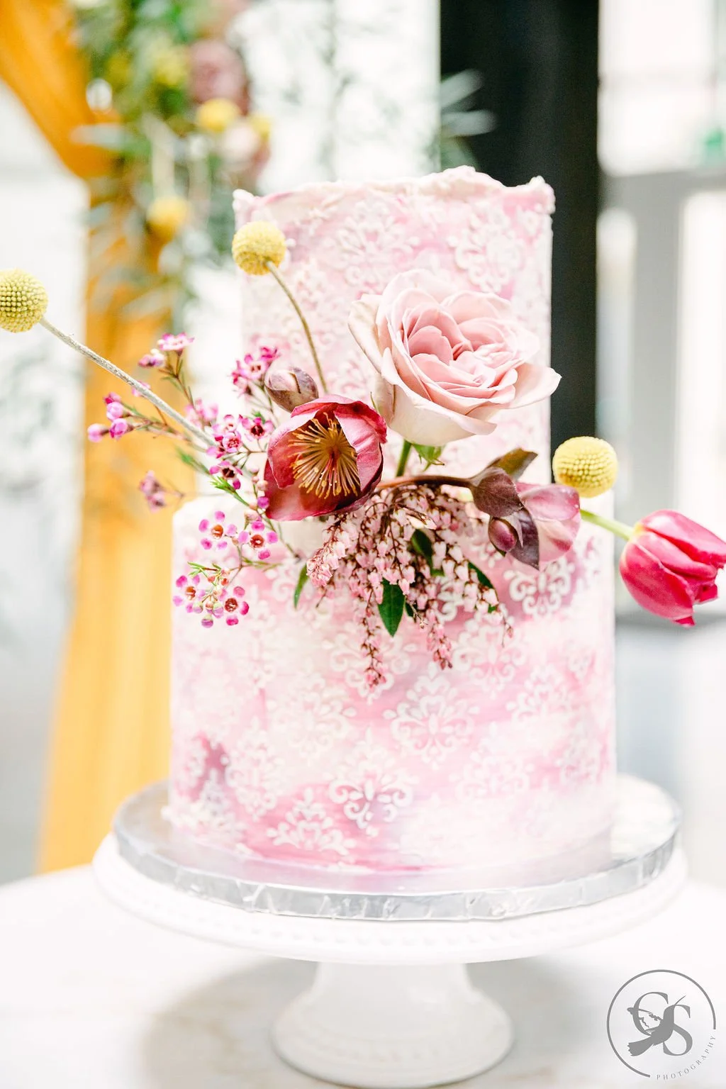   Portland Oregon wedding cake by Tres Belle Desserts featuring pink patterned buttercream and fresh florals, displayed for an elegant reception.  