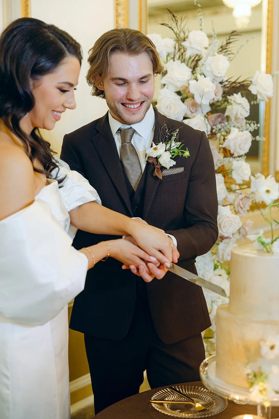   Bride and groom cutting a Portland Oregon wedding cake during an elegant indoor wedding reception with floral décor.  