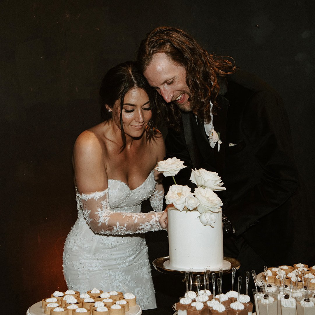 bride and groom cutting cake in wedding clothing in oregon.