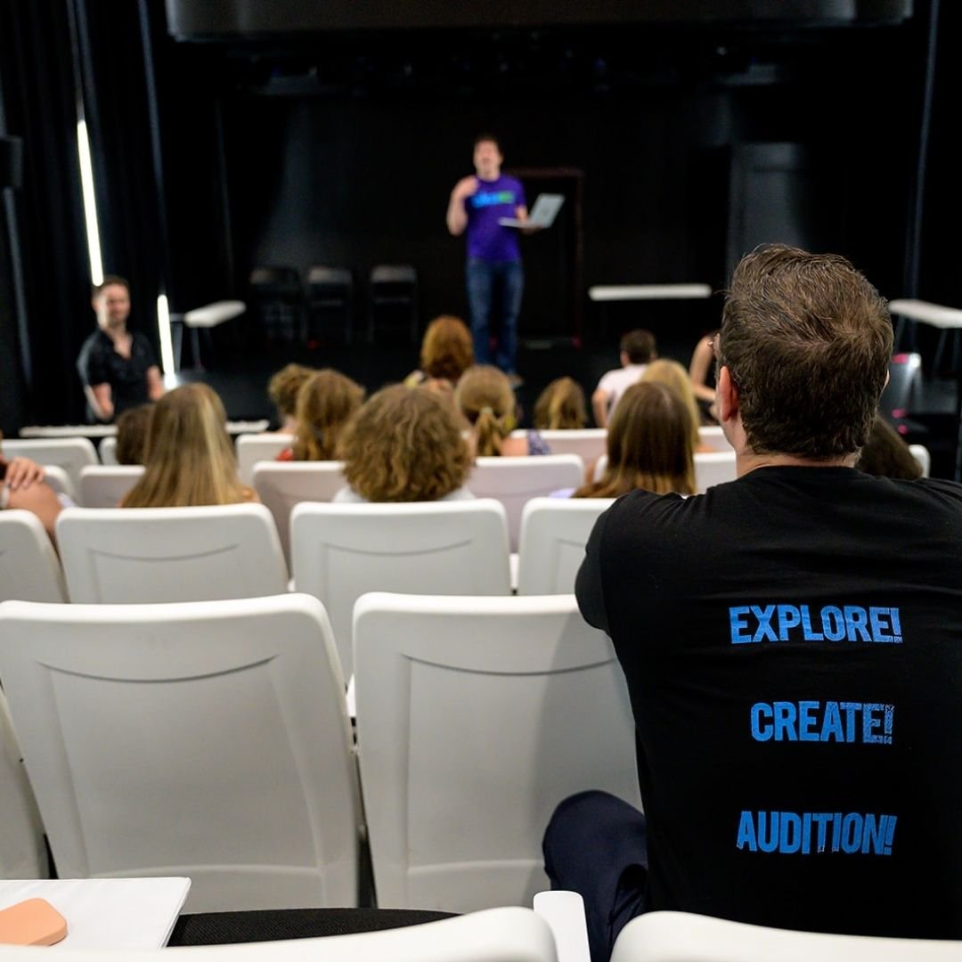 Instructors in the front and back of the room with kids looking at center stage