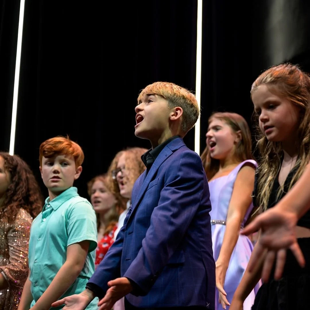 young boy singing proudly on stage
