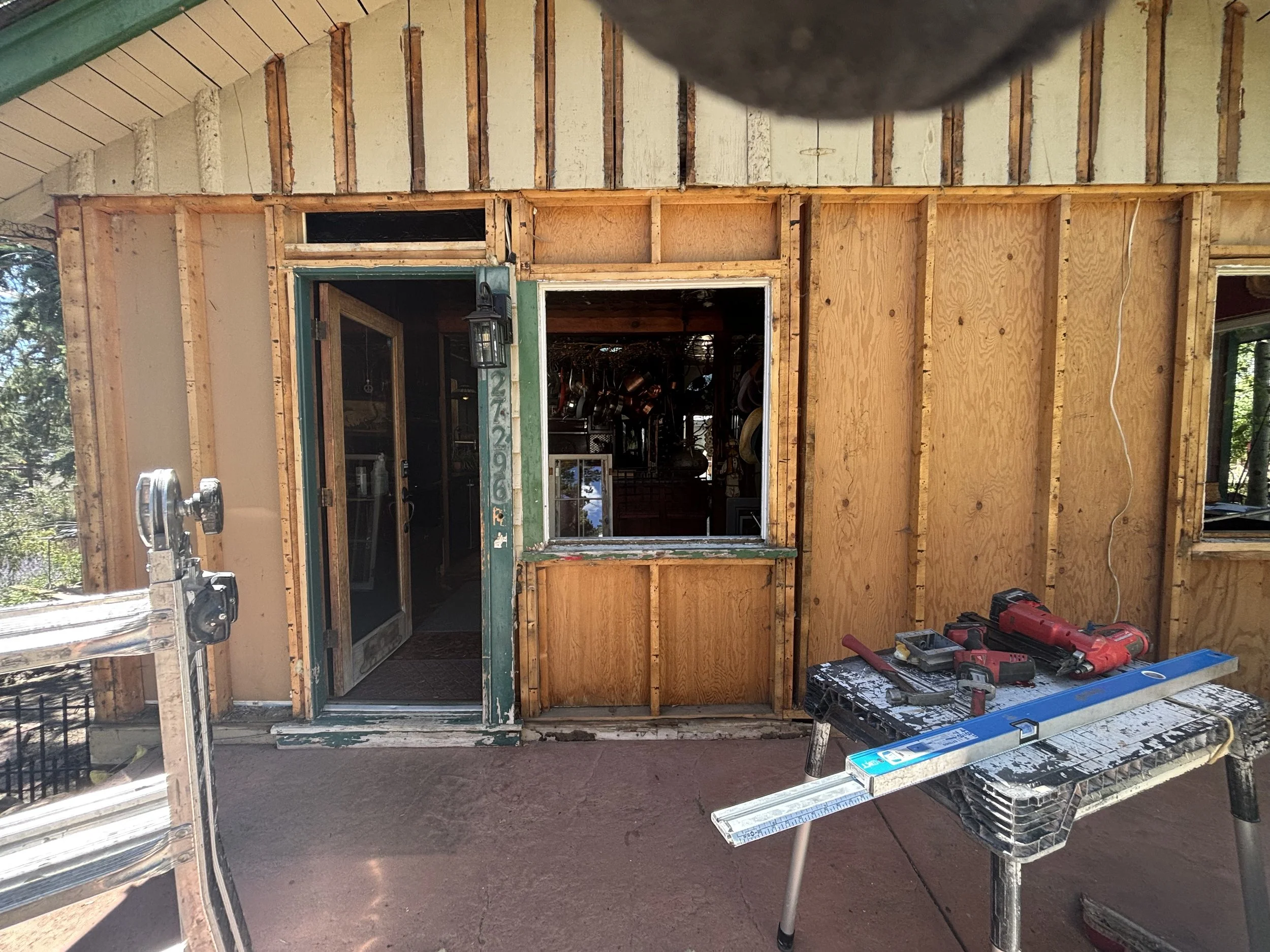 Residential exterior remodeling and construction by Otto Custom Builders, featuring exposed wood framing, plywood sheathing, door and window openings, and construction materials in the Denver Metro area, Colorado.