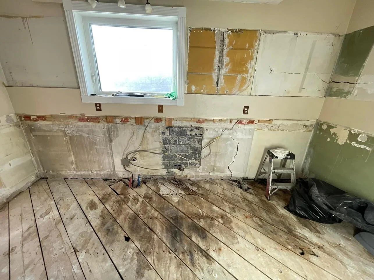 Kitchen demolition and remodeling by Otto Custom Builders, featuring exposed electrical wiring, damaged plaster walls, and weathered wood flooring. Residential kitchen renovation, interior demolition, and remodeling services in Denver, Aurora.