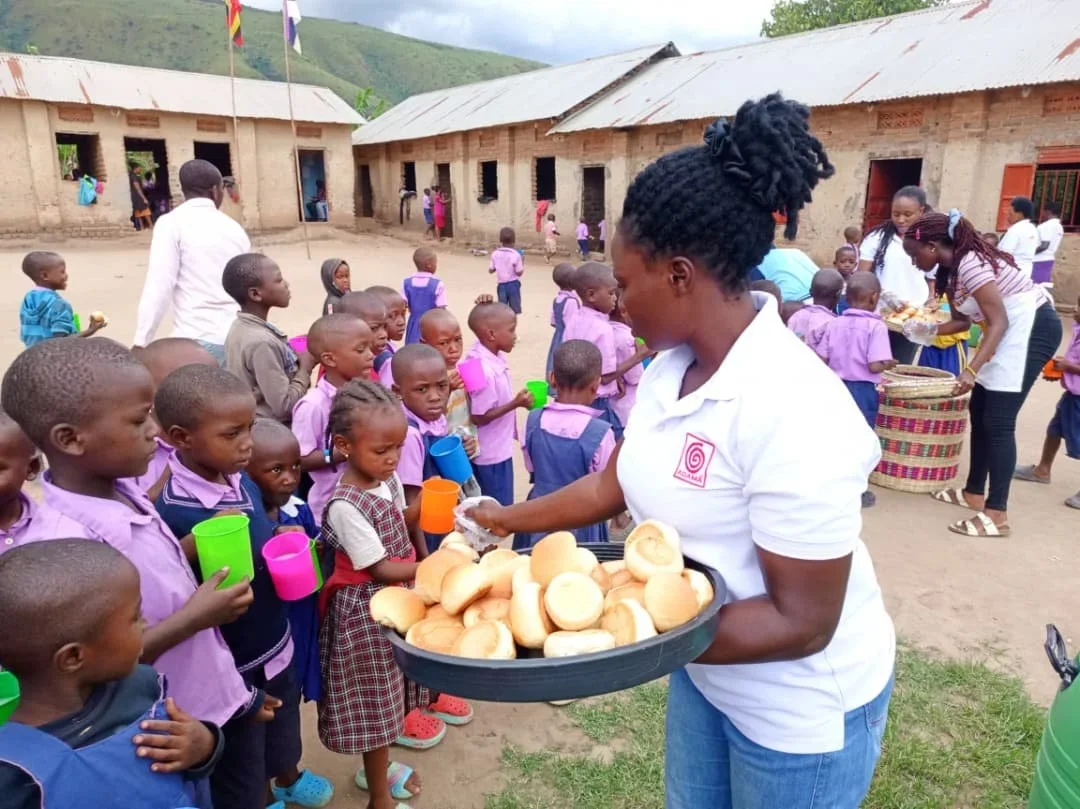 Woman passing out bread to children in an African village.