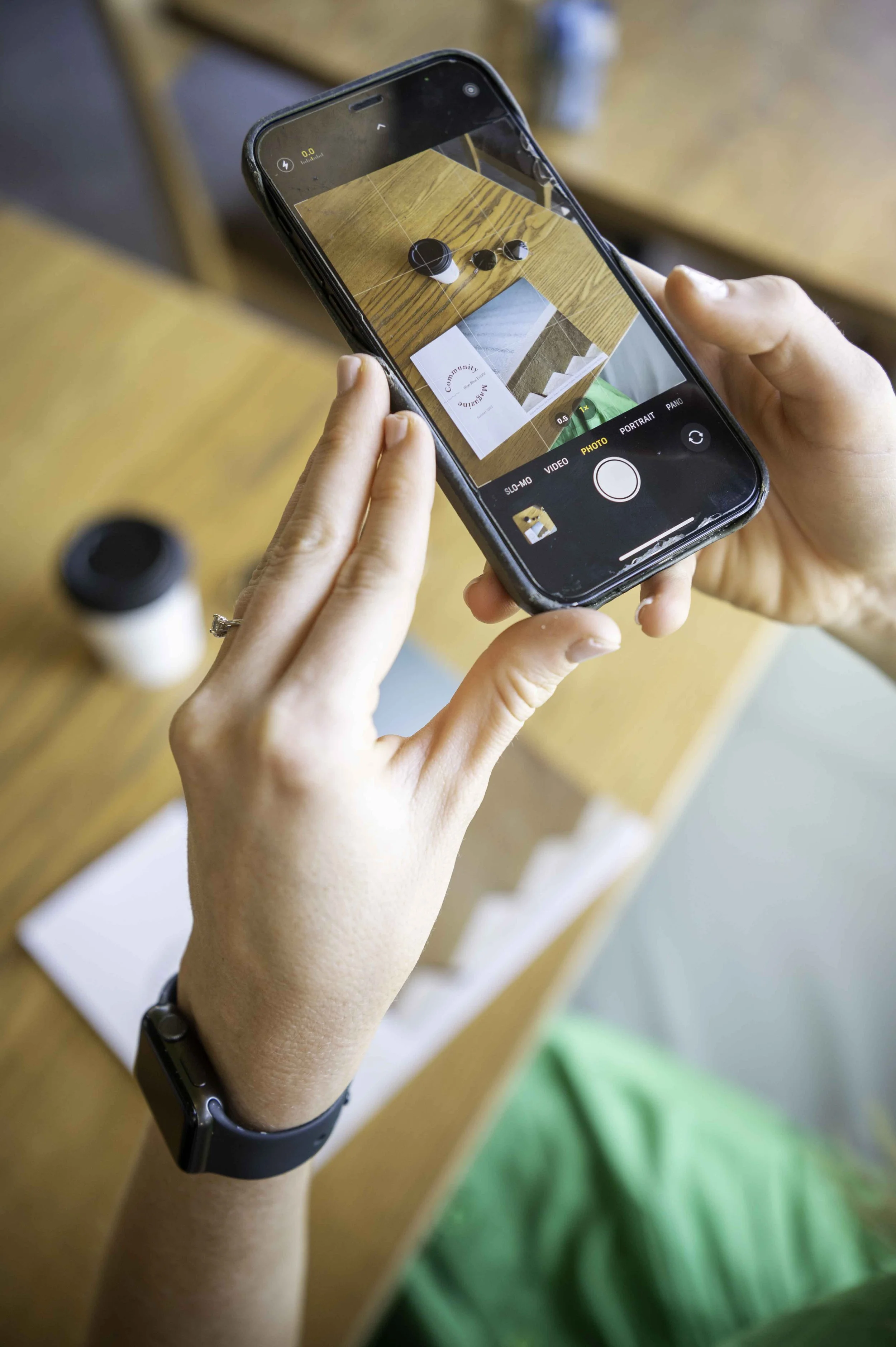 A woman taking a photo of a magazine with her smart phone.