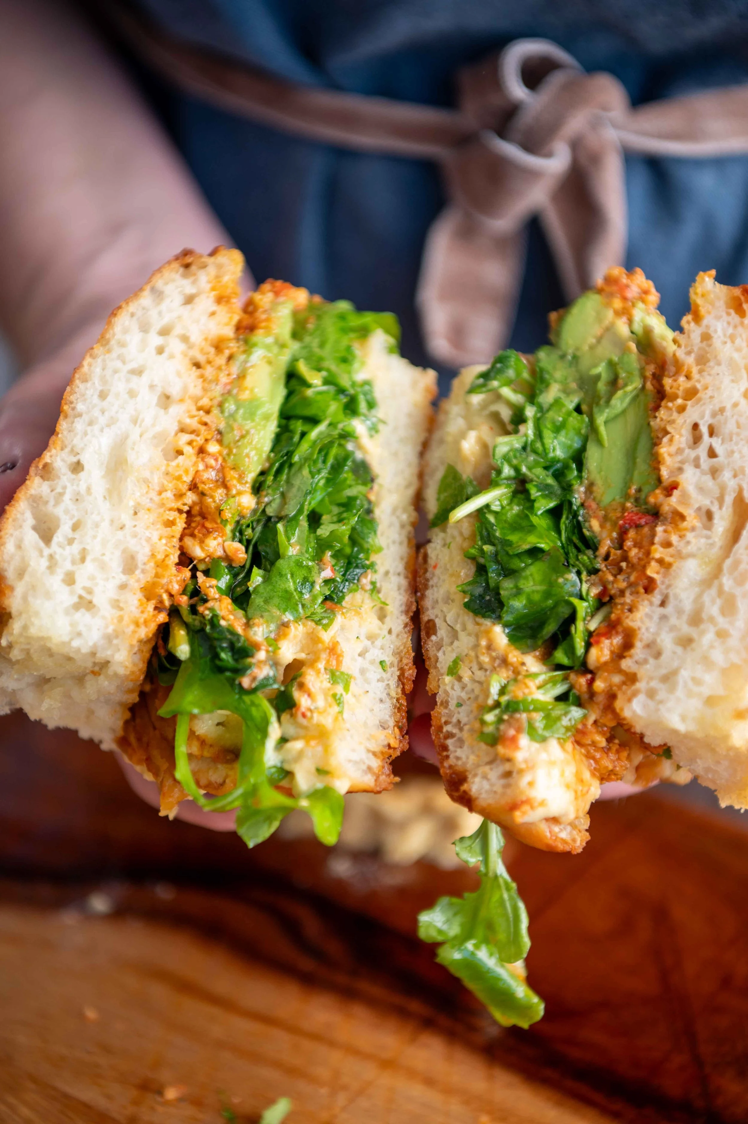 Close-up of a sandwich with shredded chicken, lettuce, and avocado between slices of bread. For Rose’s Deli.