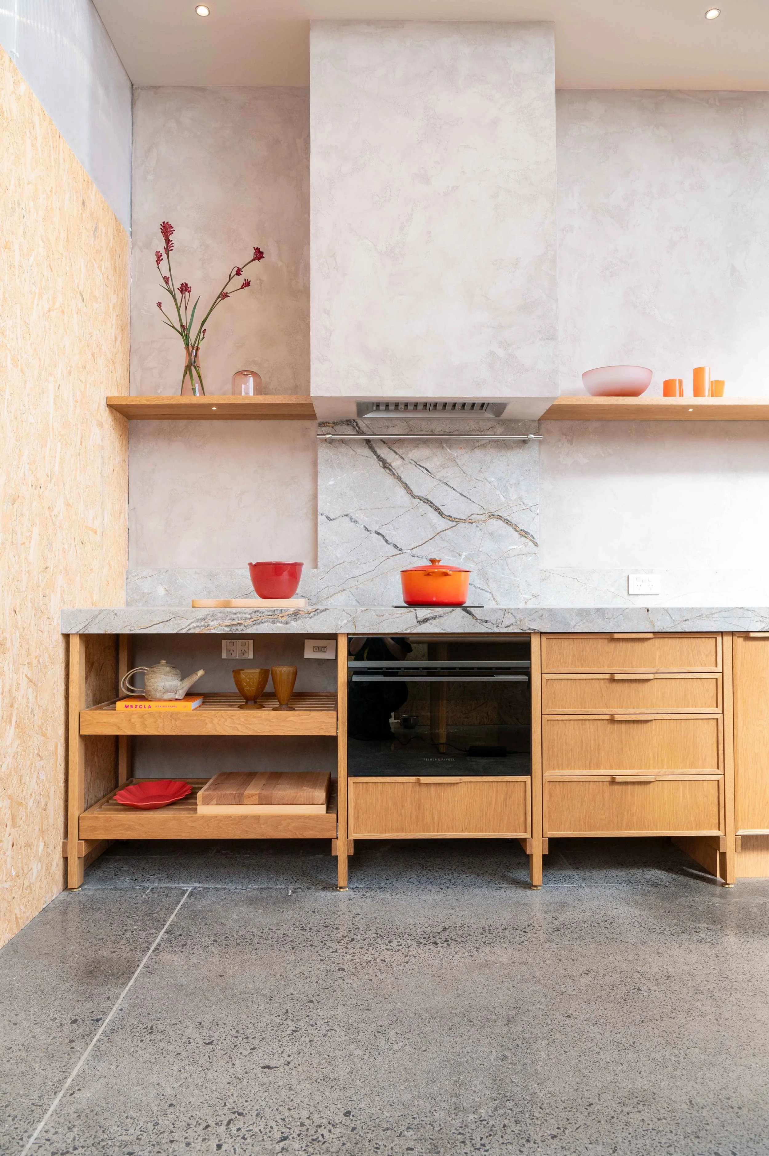 Modular Kitchen with marble bench top and splash back. Light timber cabinetry. Orange and pink props.