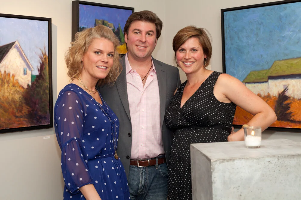 Drawing Room owners Kenleigh & Mike Larock and gallery curator Cameron Schmitz stand in front of works from this summer's En Plein Air exhibition.