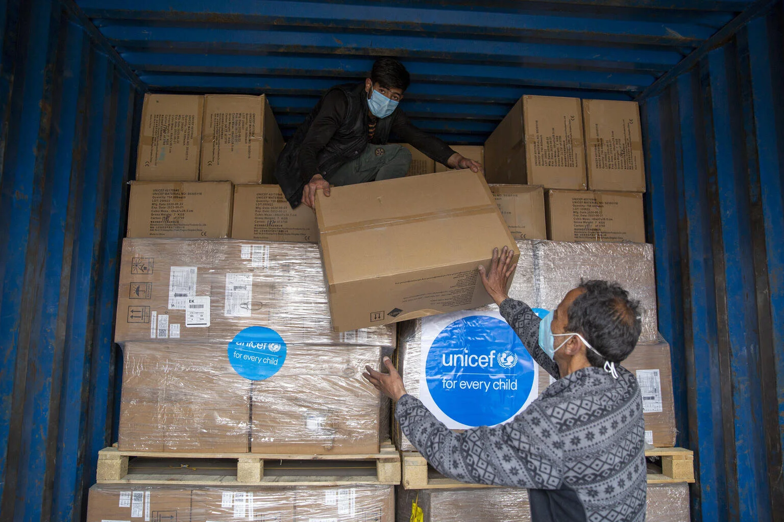 Workers unload cartons containing face masks and face shields supplied by UNICEF to state health department, from a truck inside Government Medical College, Srinagar, Jammu &amp; Kashmir. In response to rapid and rising COVID-19 cases in India, UNICEF's supply division quickly shipped 1.68 million face masks and more than hundred thousand face shields to India so that frontline health workers have enough of the right equipment to stay safe against COVID-19. (Photo: Altaf Ahmad)  ©UNICEF/UN0463111/Altaf Ahmad