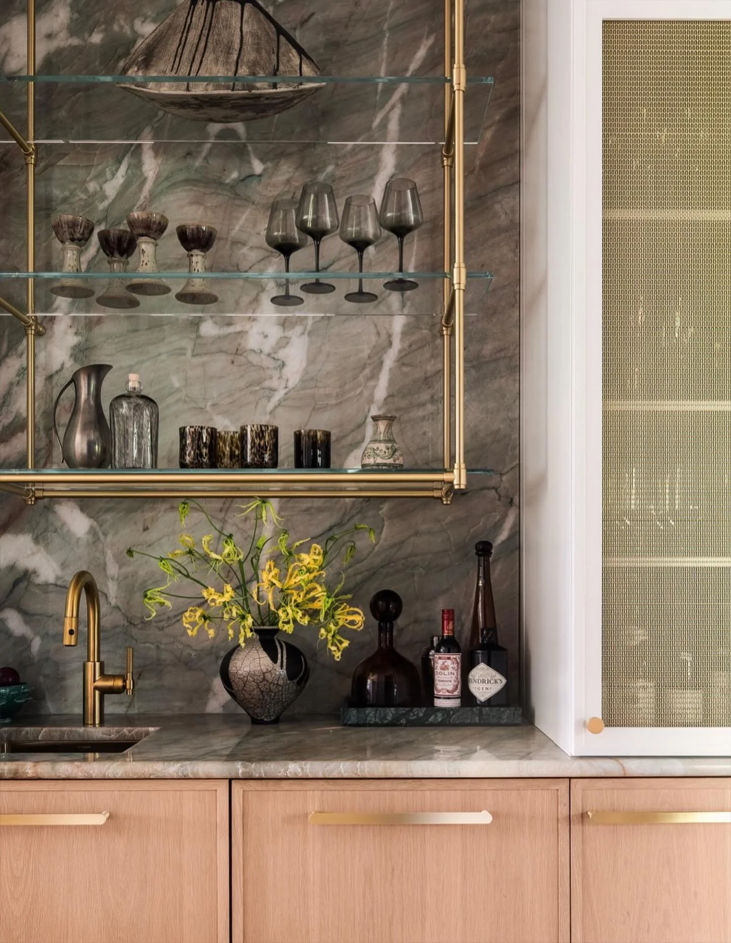 A moody mix of stone, brass, and glass&mdash;where every detail was designed to feel both collected and intentional. From the sculptural shelving to the green veined stone backdrop, this bar moment blends functionality with artistry for effortless en