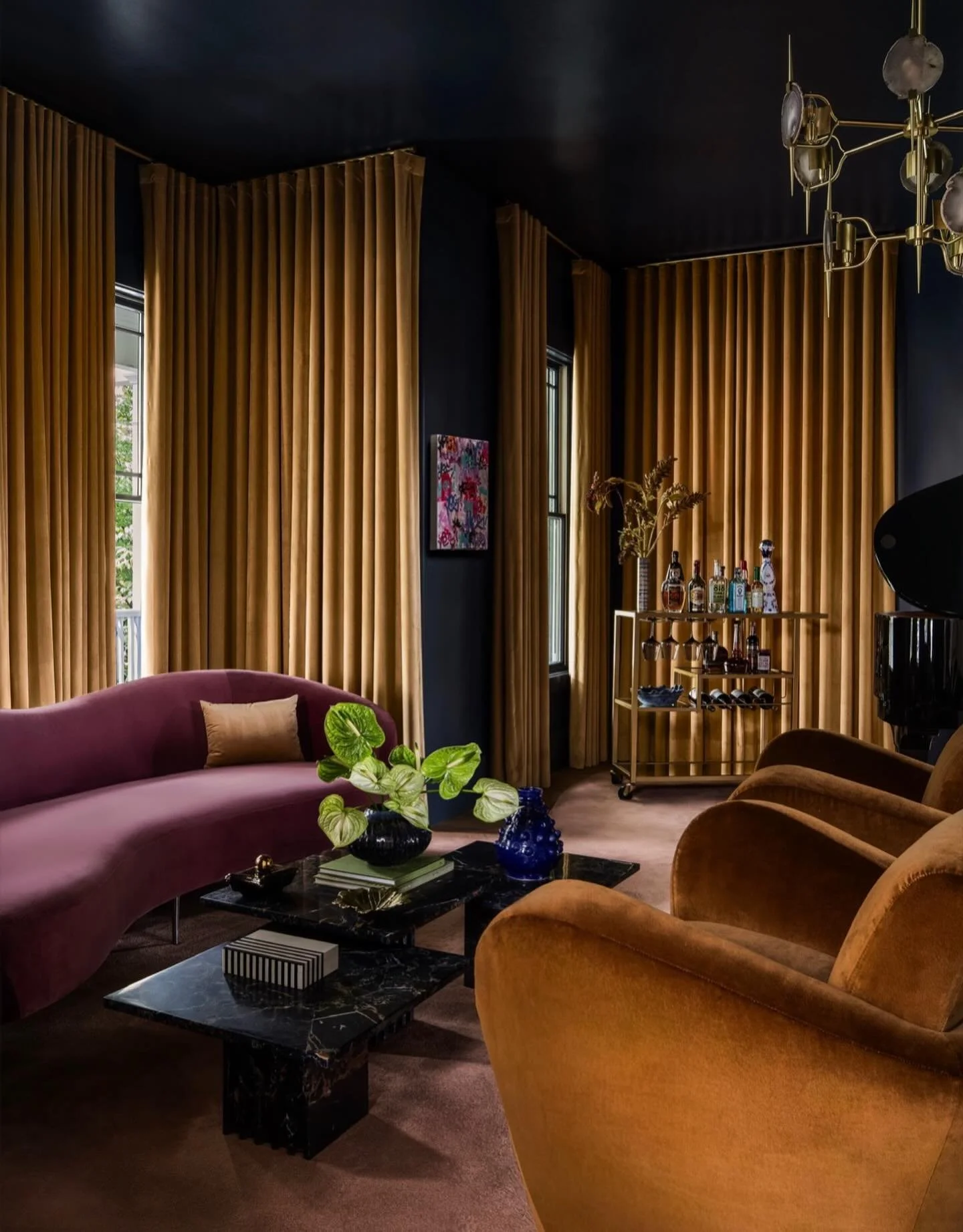 Moody hues, sculptural silhouettes, and layers of velvet create a piano lounge space that feels both intimate and elevated. From the rich drapery to the curved seating and dramatic ceiling, every detail was designed to envelop the room in warmth, dep