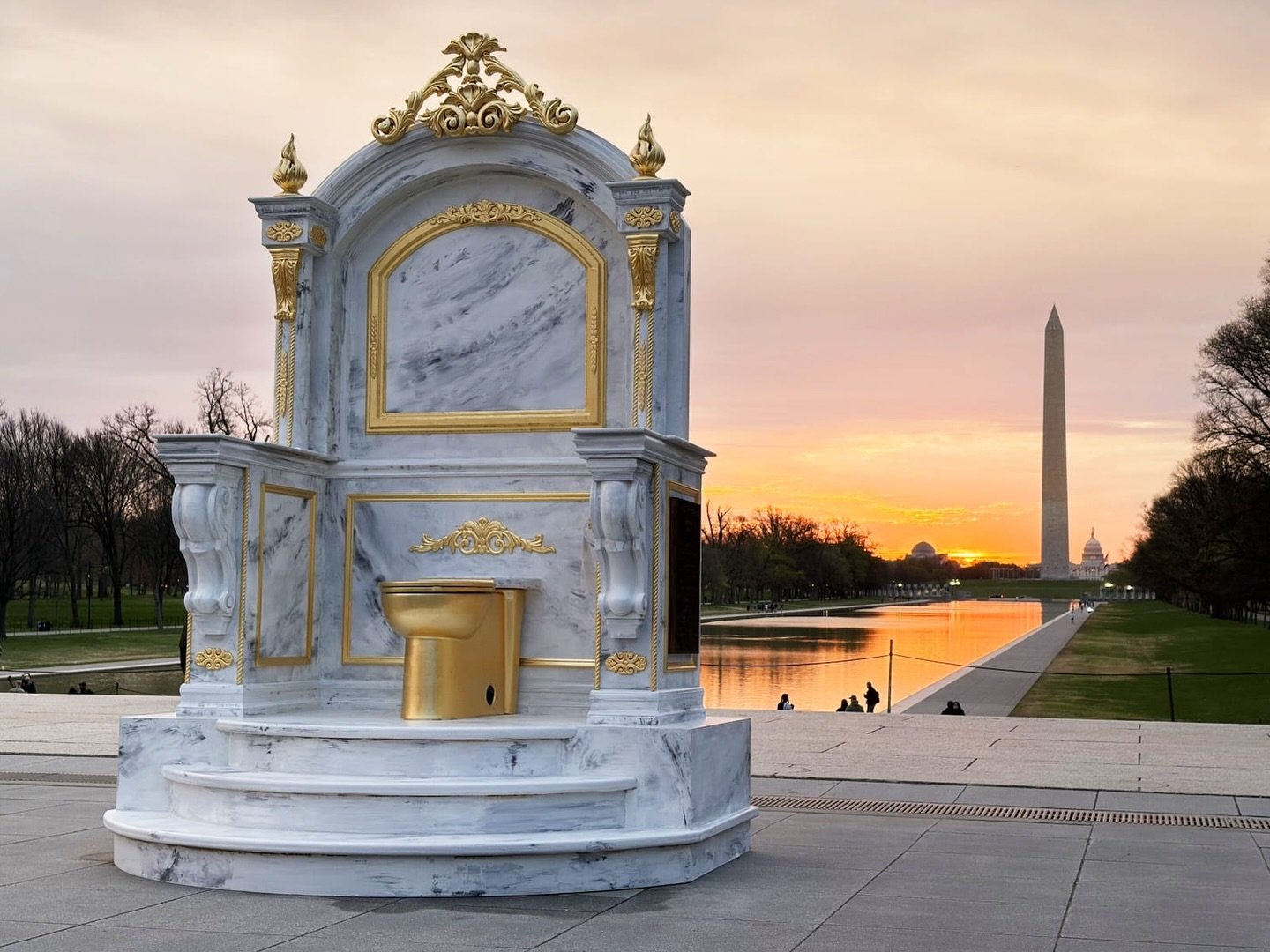 The guerrilla art collective the Secret Handshake, who are behind the iconic statue of Trump and Epstein frolicking and holding hands, installed a faux marble statue of a giant gold toilet across from the Lincoln Memorial on the National Mall yesterd